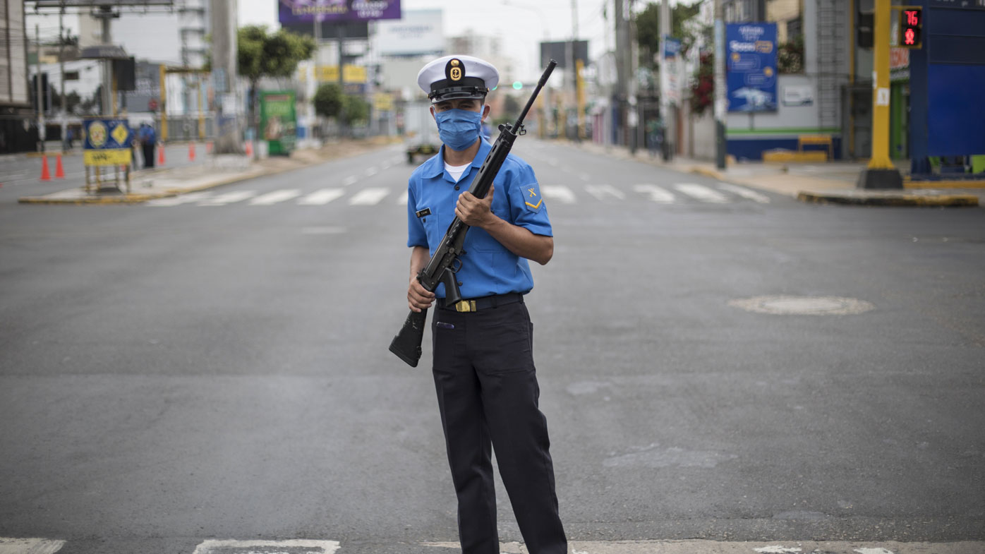 A Marine wearing a protective mask as a precaution against the spread of the new coronavirus stands guard to keep the streets cleared, in Lima, Peru.