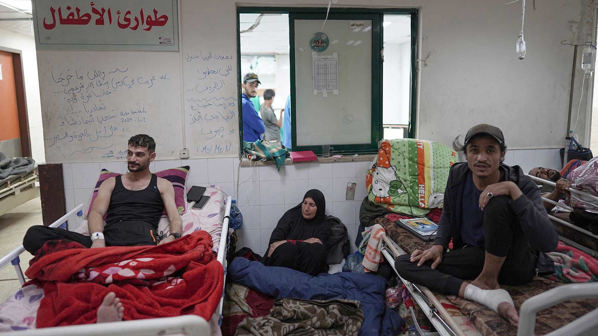 A Palestinian woman sits on the floor between patients at the Al Aqsa Martyrs Hospital in Deir Al-Balah in the central Gaza Strip on April 3.