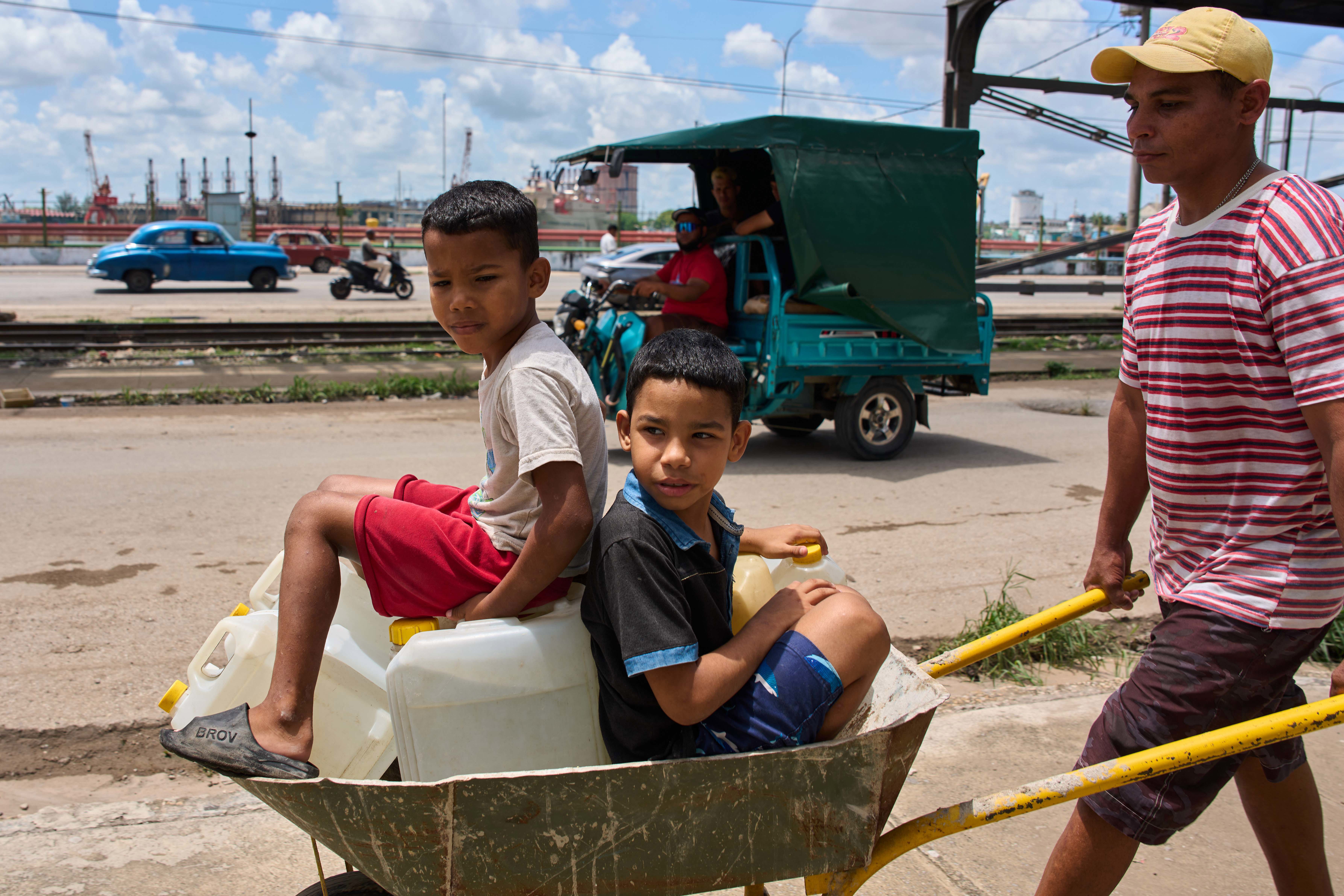 A man transports containers of water with his children in Havana, Cuba.