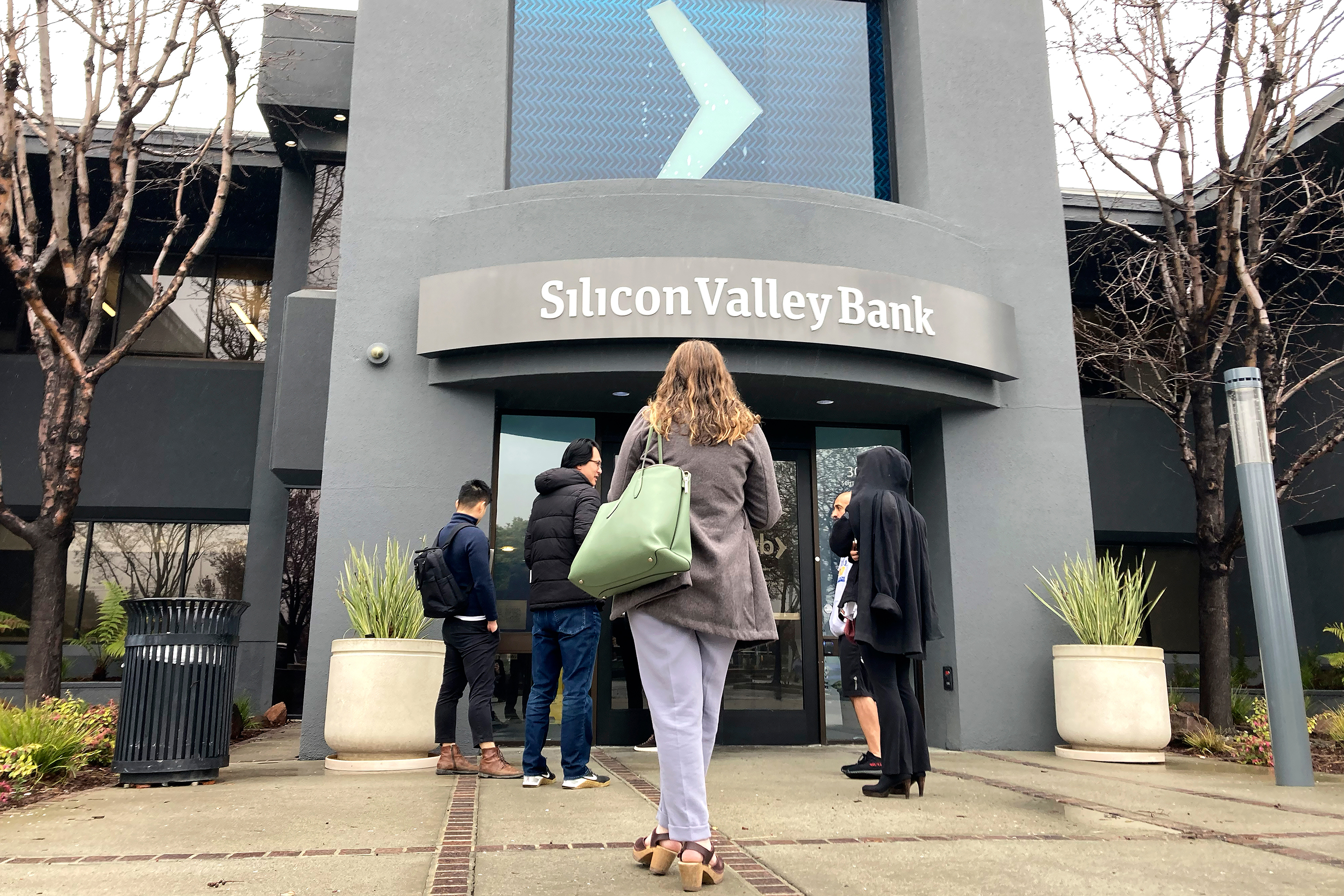 People stand outside of an entrance to Silicon Valley Bank in Santa Clara, Calif., Friday, March 10, 2023.