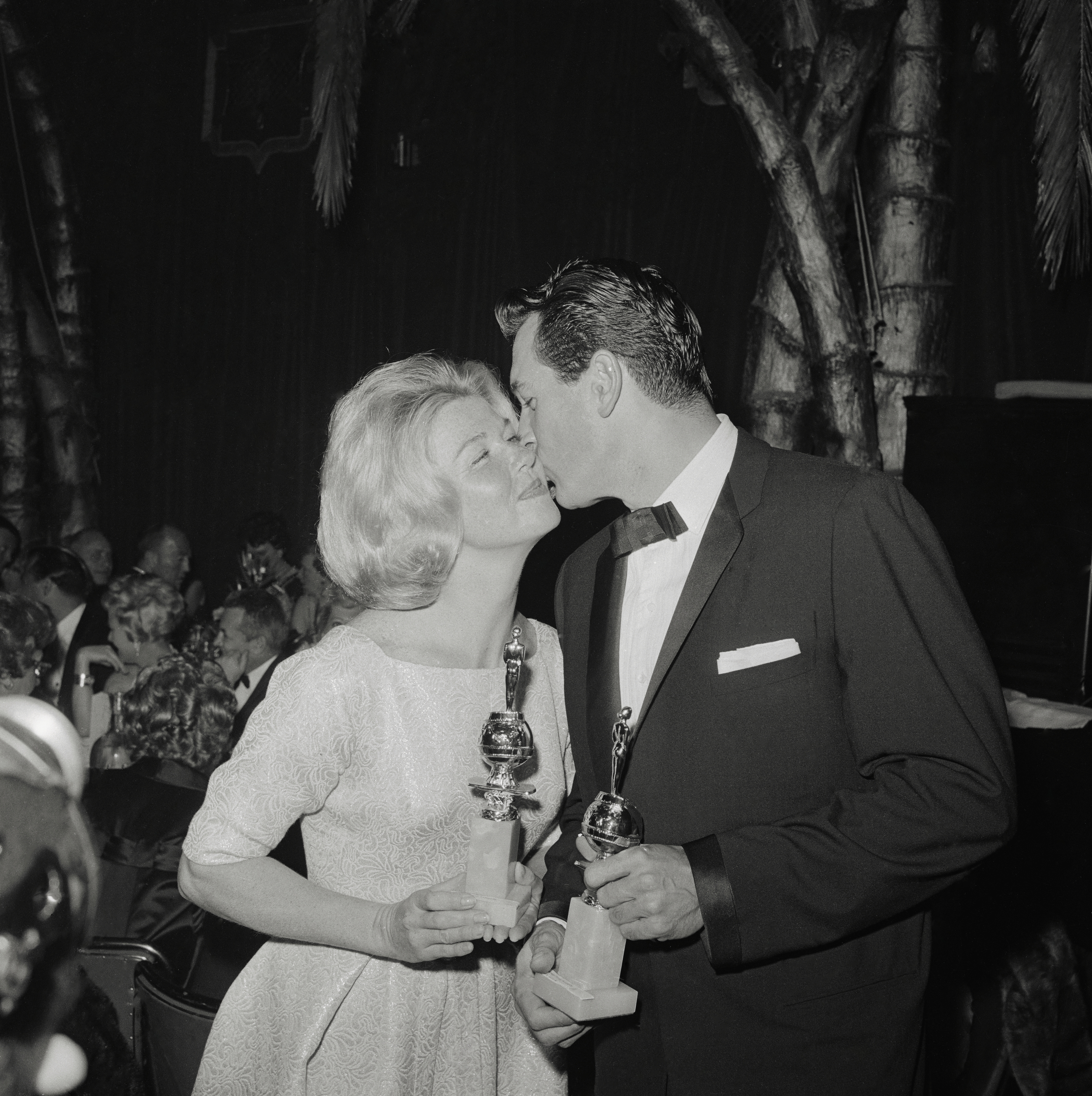 Rock Hudson kisses Doris Day as they hold their Golden Globe Awards at the ceremony in 1960