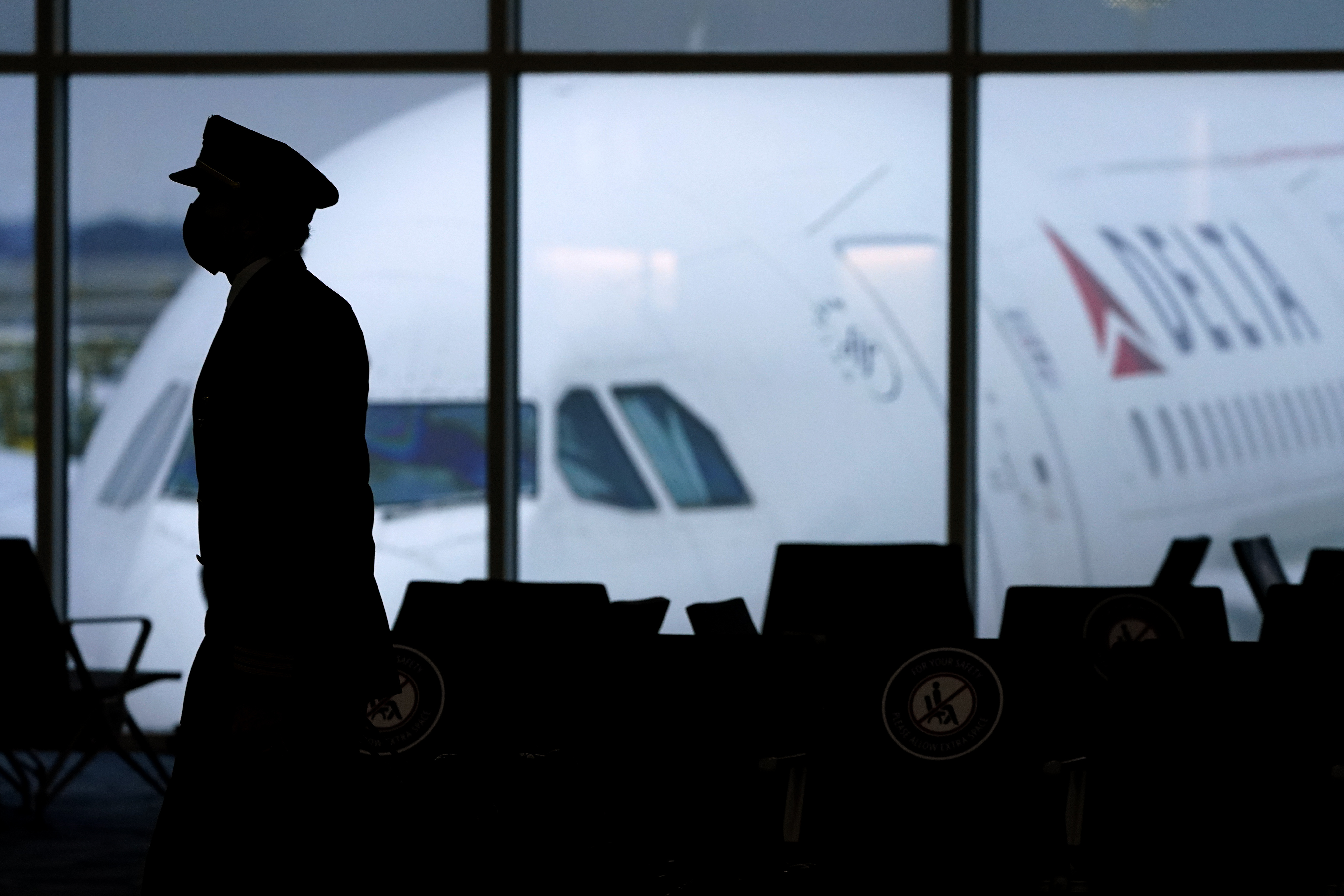 A Delta Airlines pilot wears a face mask to help prevent the spread of the new coronavirus as he walks through a terminal at Hartsfield-Jackson International Airport in Atlanta, Thursday, Feb. 18, 2021. (AP Photo/Charlie Riedel)