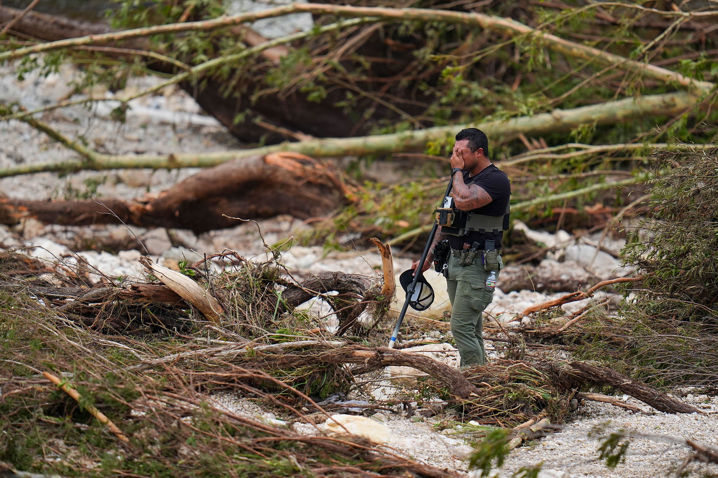 A Sheriff's deputy pauses while combing through the banks of the Guadalupe River near Camp Mystic on July 5 in Hunt, Texas.