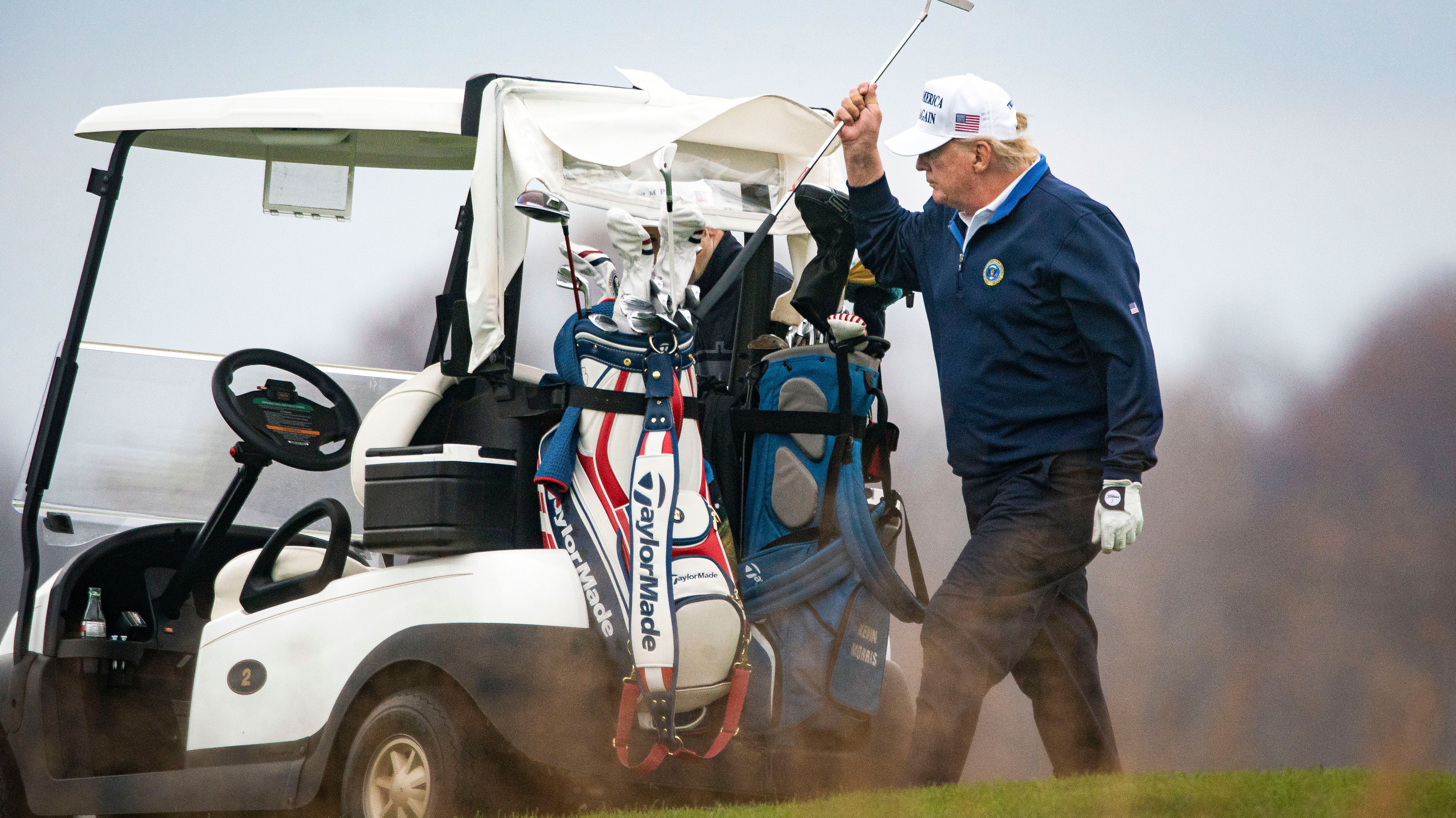 Donald Trump puts a club back in his bag after taking a shot.