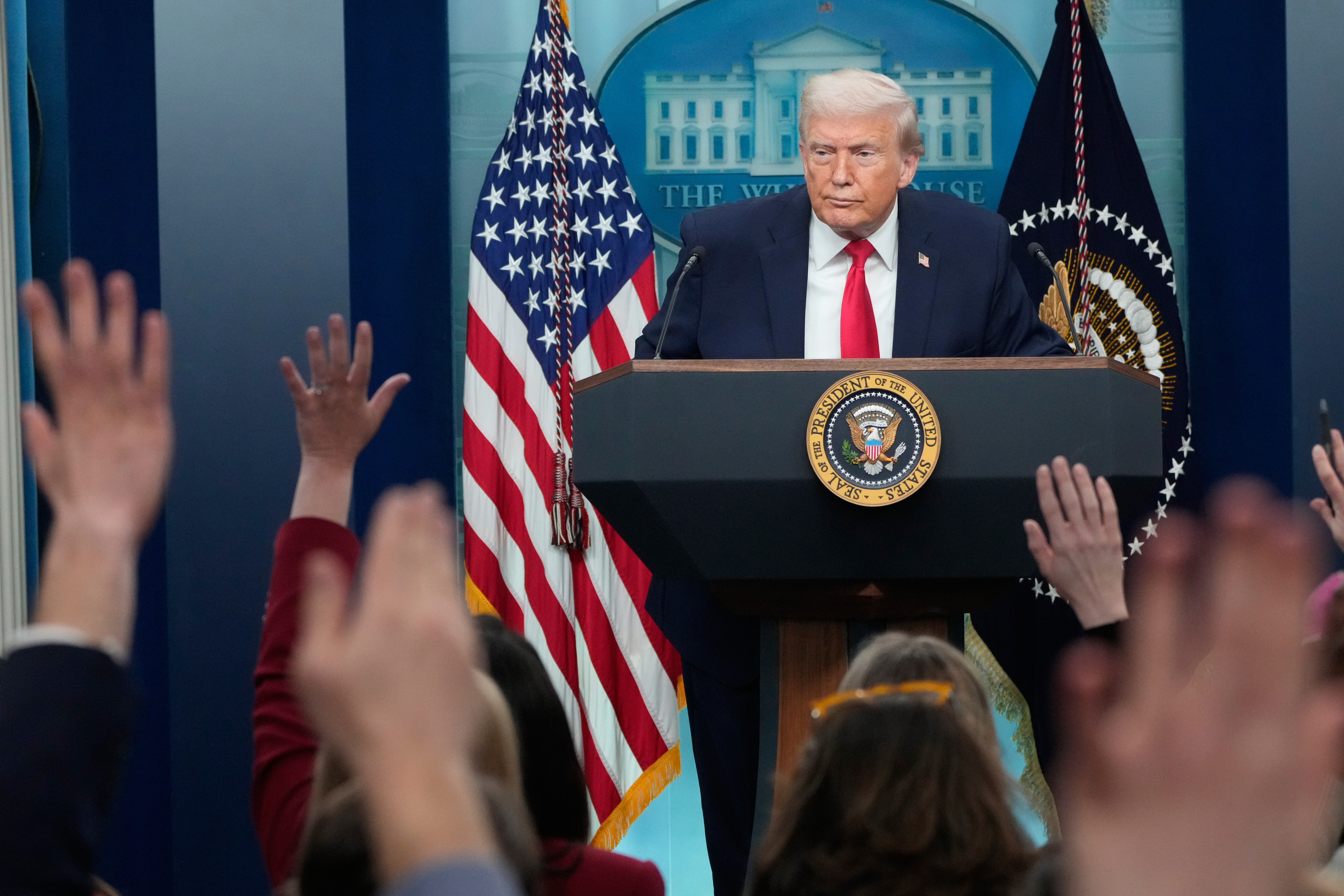 Reporters raise their hands as President Donald Trump speaks during a press briefing at the White House.
