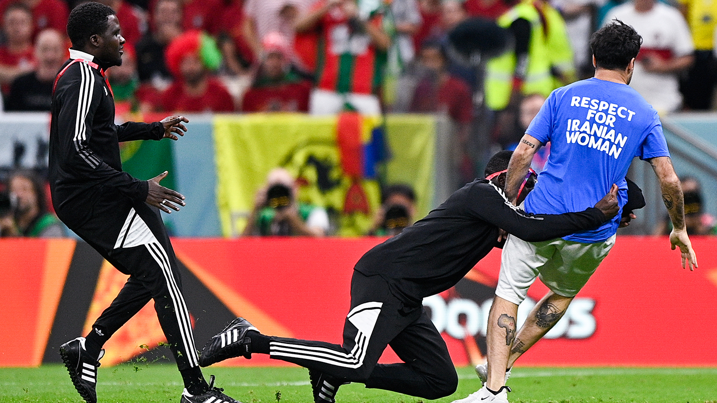 Security tackles a pitch invader during the Portugal-Uruguay match.