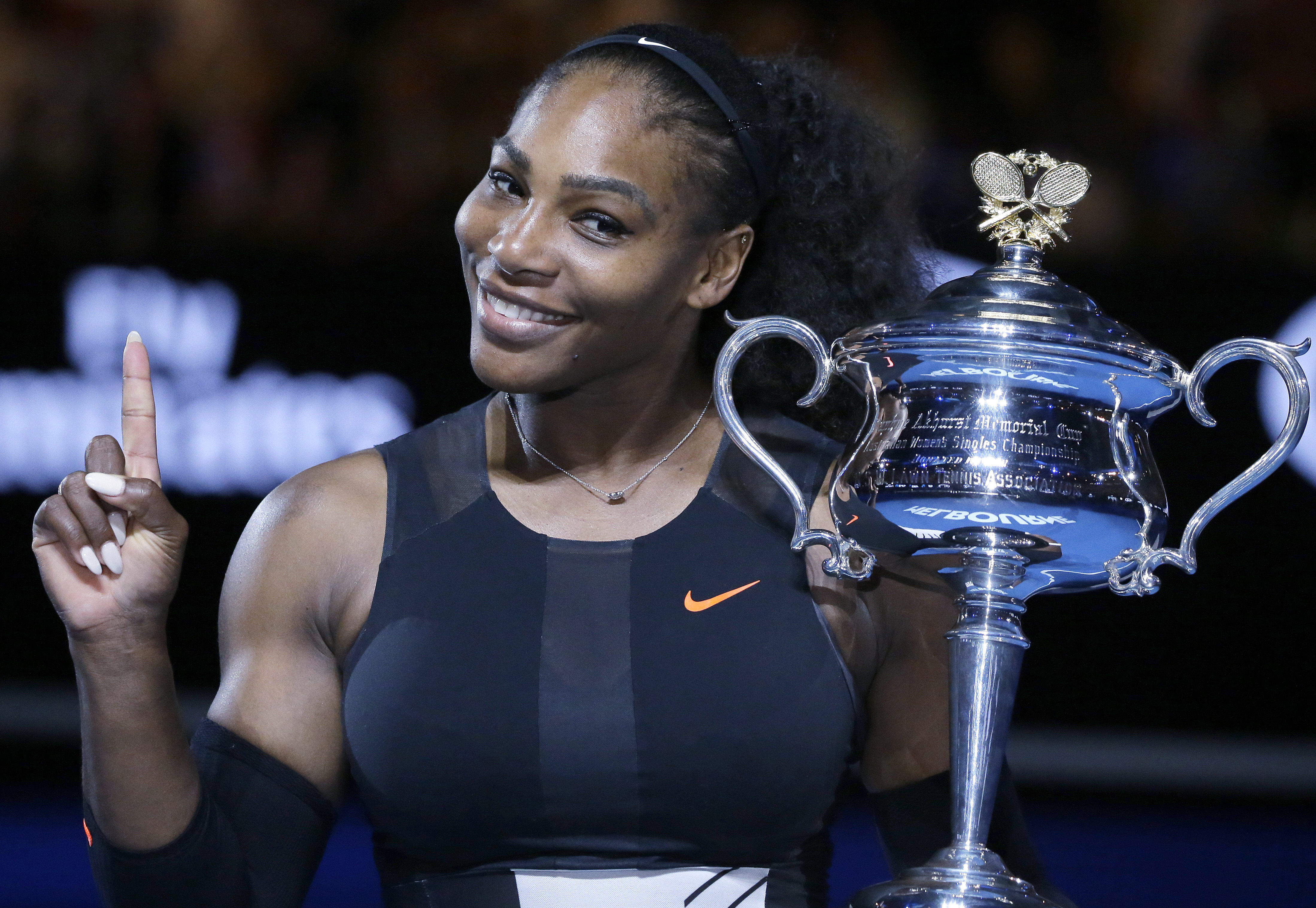 In this Jan. 28, 2017, file photo, Serena Williams holds up a finger and her trophy after defeating her sister, Venus, in the women's singles final at the Australian Open tennis championships in Melbourne, Australia. 
