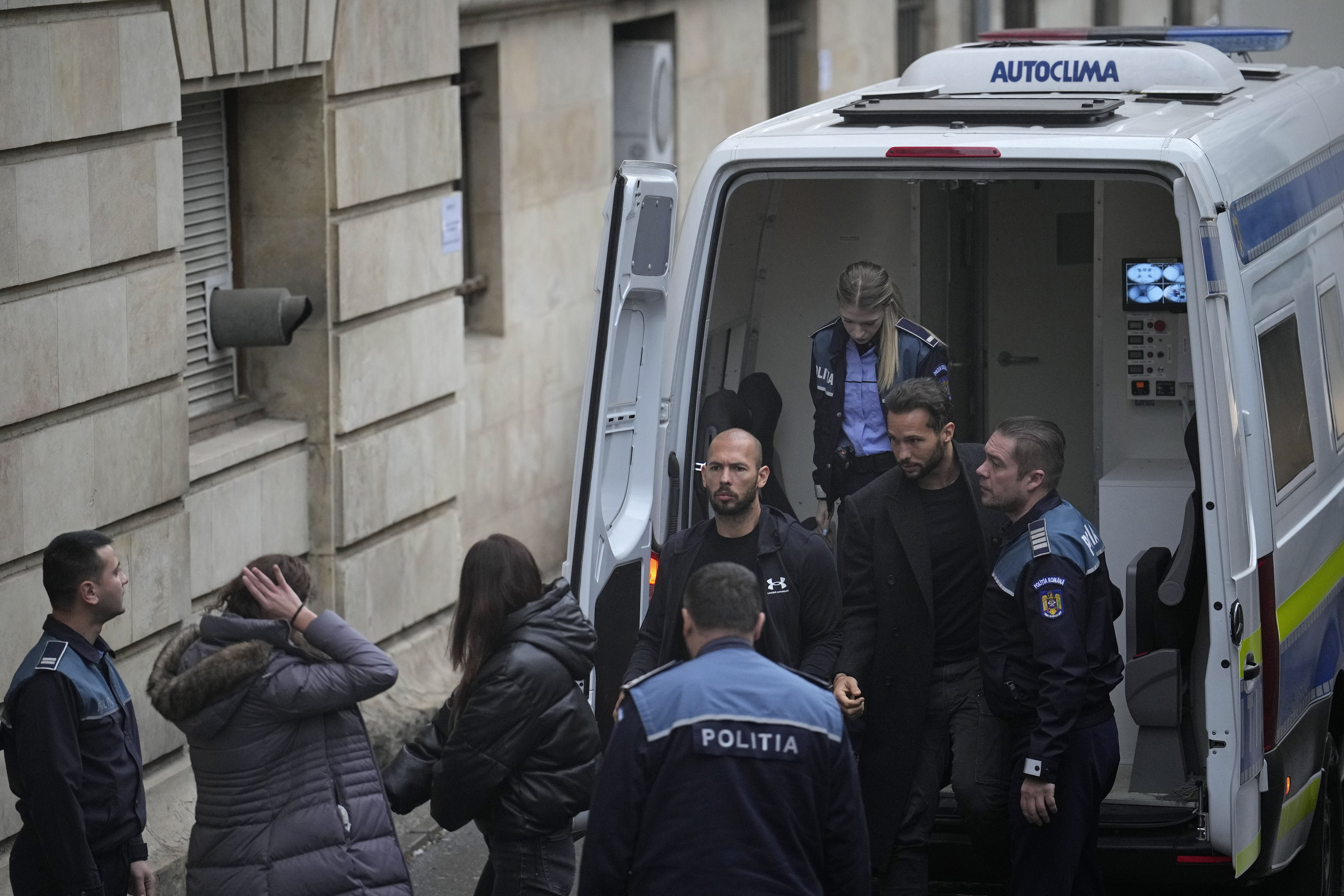 Andrew Tate, centre, and his brother Tristan, second right, are brought by police officers to the Court of Appeal, in Bucharest, Romania, Tuesday, Jan.10, 2023. Andrew Tate, a divisive social media personality and former professional kickboxer, was detained last month in Romania on charges of human trafficking and rape, and later arrested for 30 days after a court decision. (AP Photo/Vadim Ghirda)