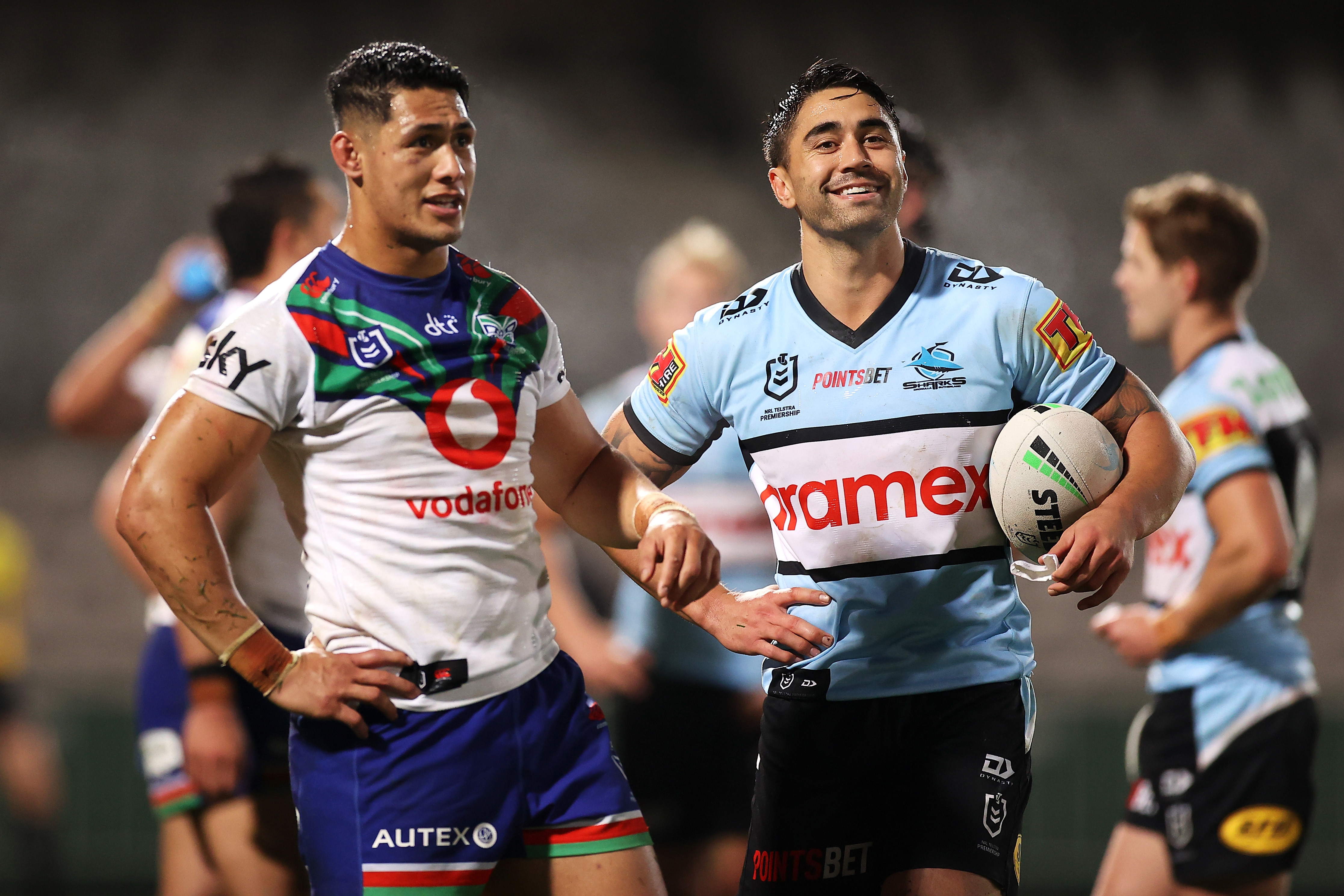 Shaun Johnson of the Sharks and Roger Tuivasa-Sheck of the Warriors share a joke as they watch the big screen for a decision.