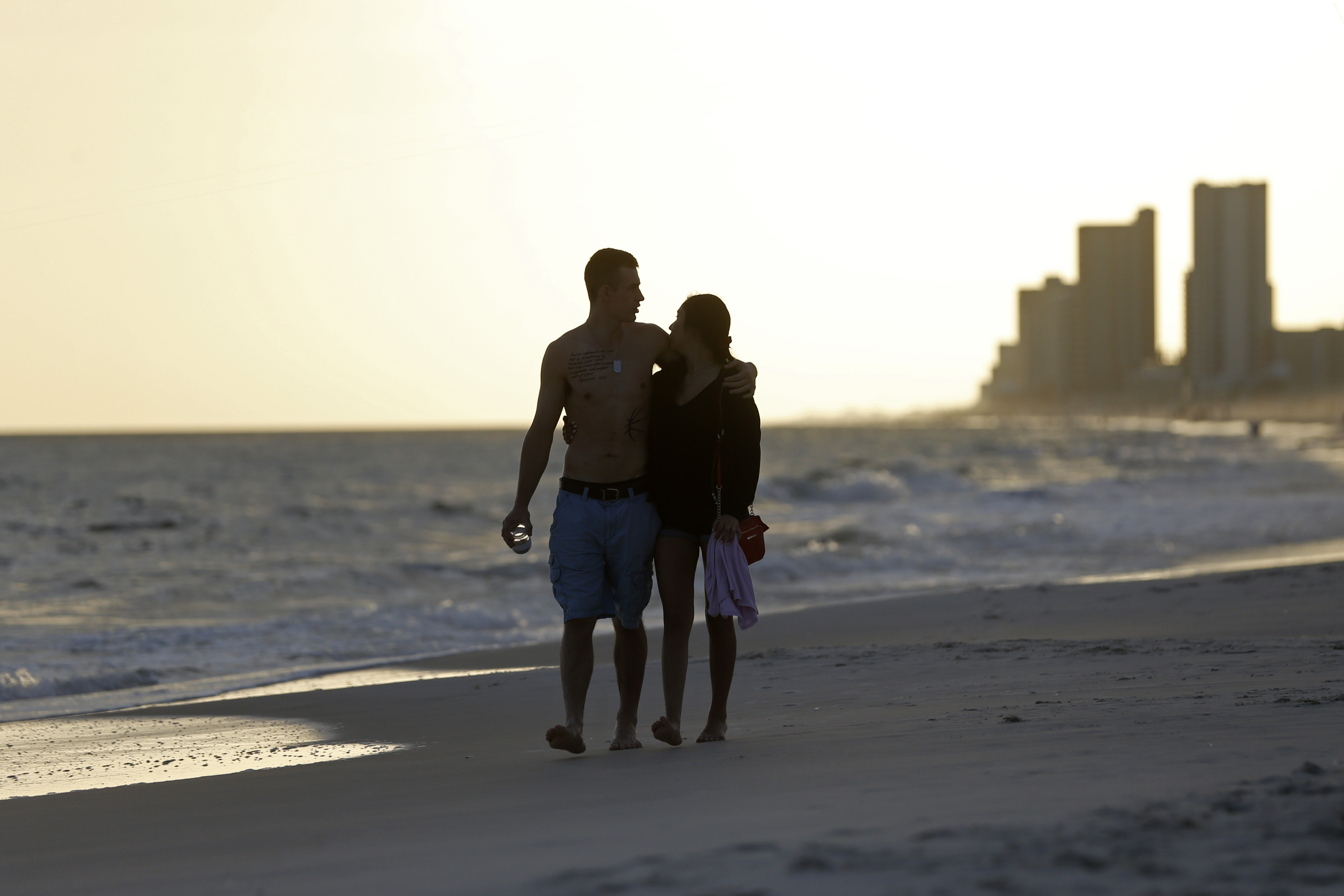 In this March 12, 2020 photo, people walk on the beach in Gulf Shores, Ala. The spring of coronavirus feels a lot like the summer of oil to residents along the Gulf Coast. Bars and restaurants are empty in Florida because of an invisible threat nearly a decade after the BP oil spill ravaged the region from the ocean floor up.