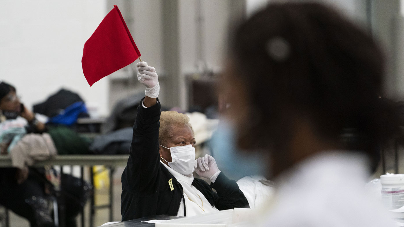 Un inspector electoral ondea una bandera para pedir ayuda mientras se cuentan las papeletas hasta las primeras horas de la mañana en Detroit, Michigan.