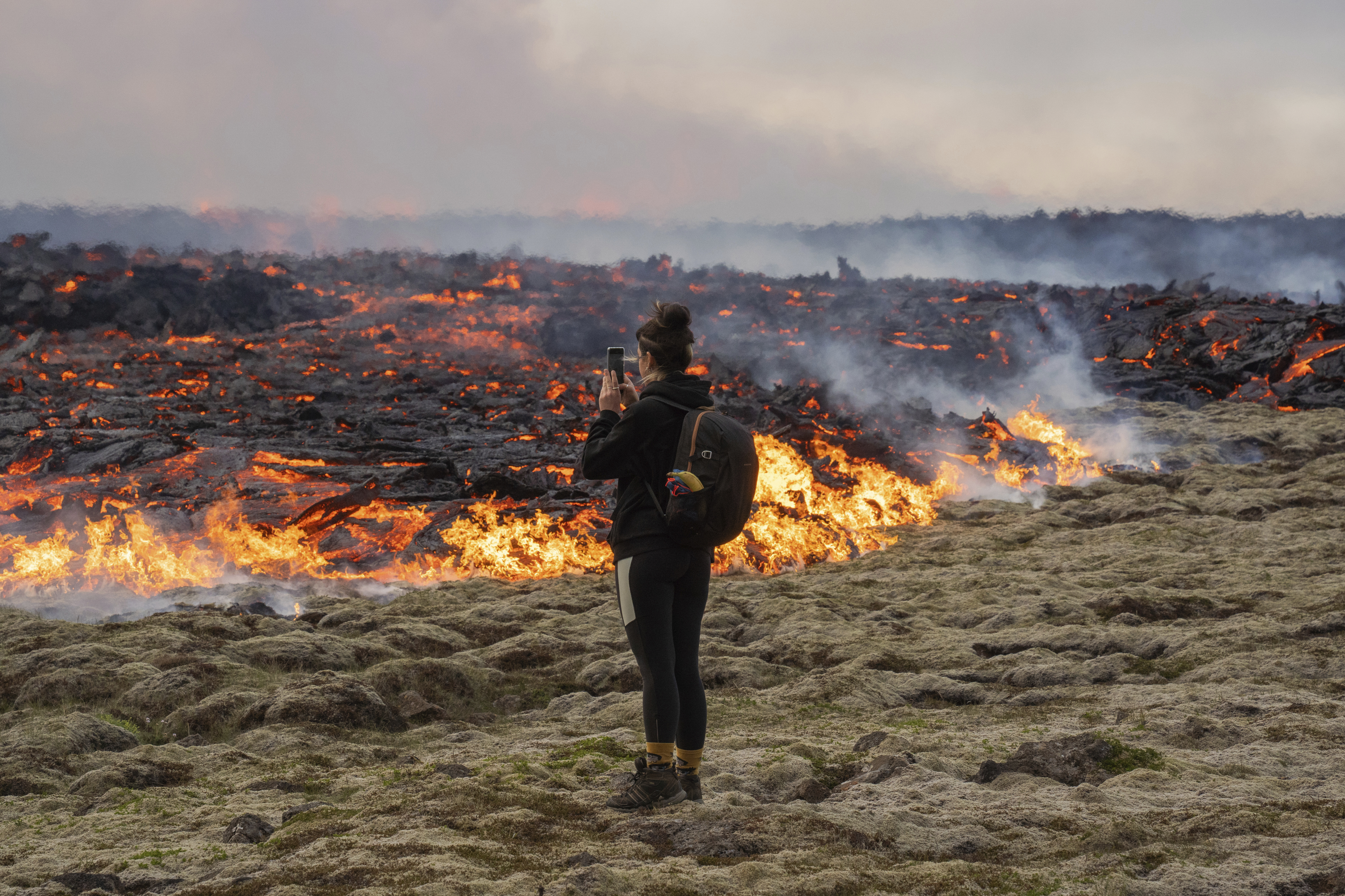 A person walks near lava emerging from a fissure of the Fagradalsfjall volcano near the Litli-Hrútur mountain, some 30 kilometres southwest of Reykjavik, Iceland, Monday July 10, 2023.  