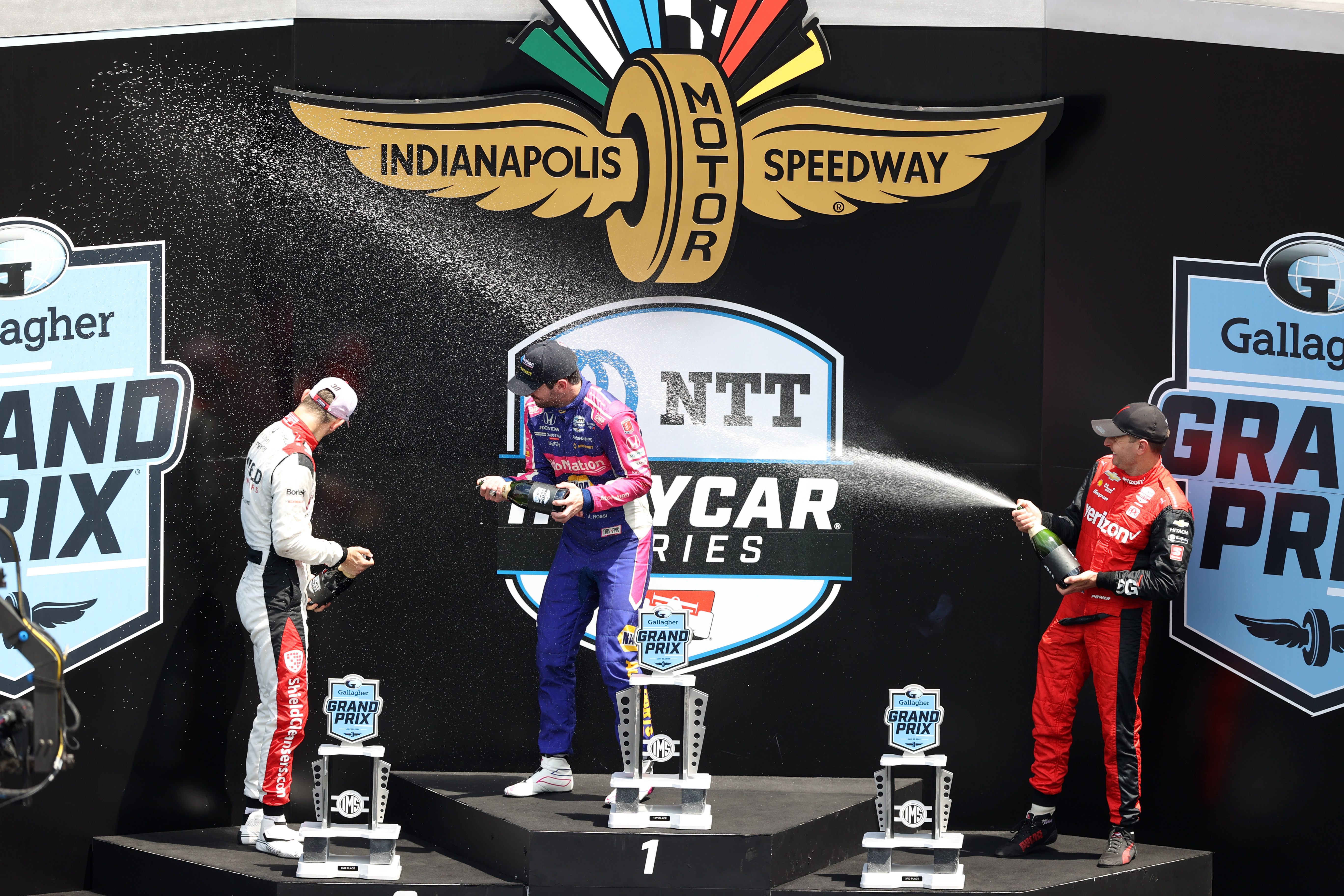 Christian Lundgaard (from left), Alexander Rossi and Will Power celebrate on the podium at Indianapolis Motor Speedway