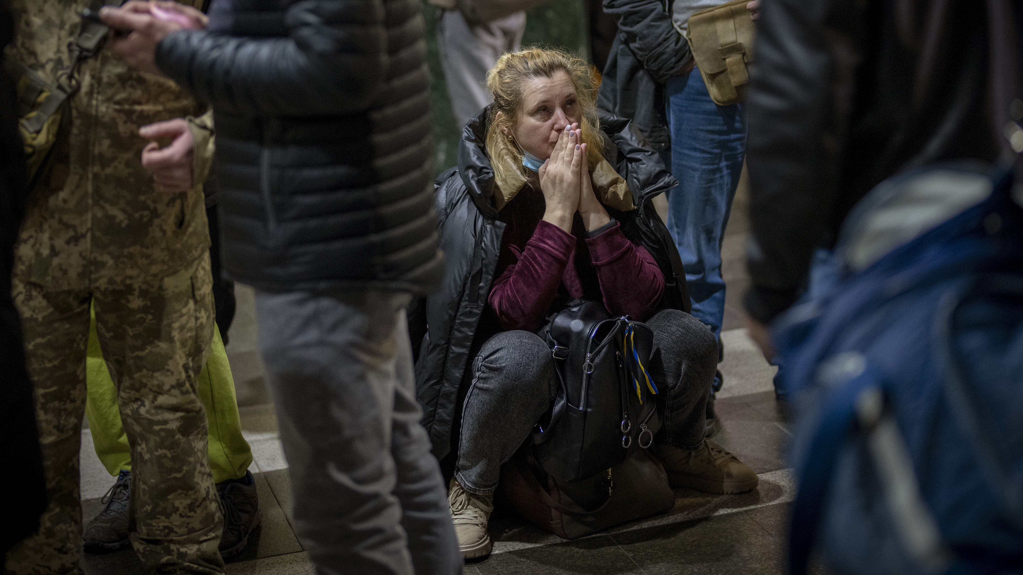 A woman sits on the floor as she waits for a train trying to leave Kyiv, Ukraine. 