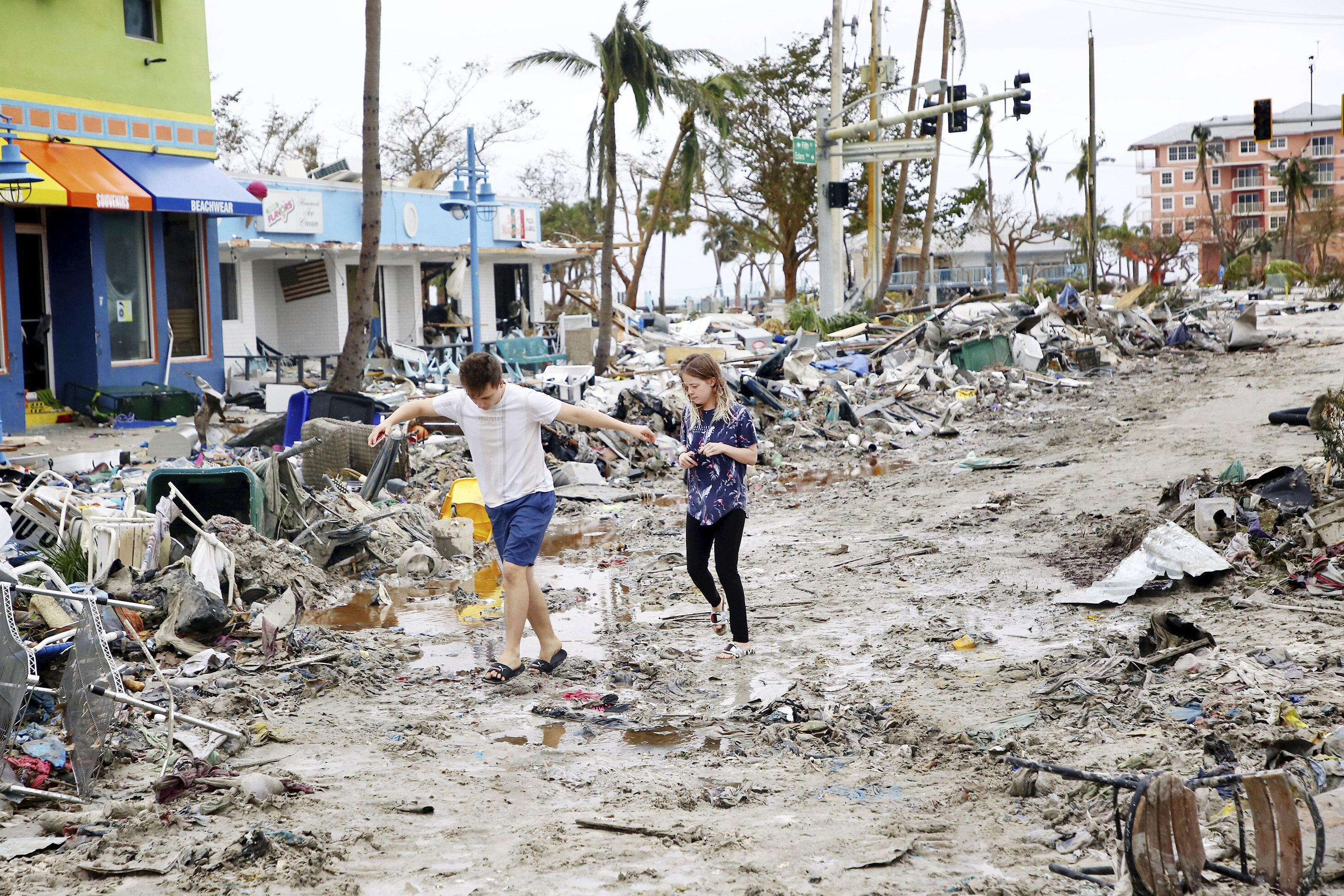 Jake Moses, 19, left, and Heather Jones, 18, of Fort Myers, explore a section of destroyed businesses at Fort Myers Beach, Florida, on Thursday, Sep 29, 2022, following Hurricane Ian 