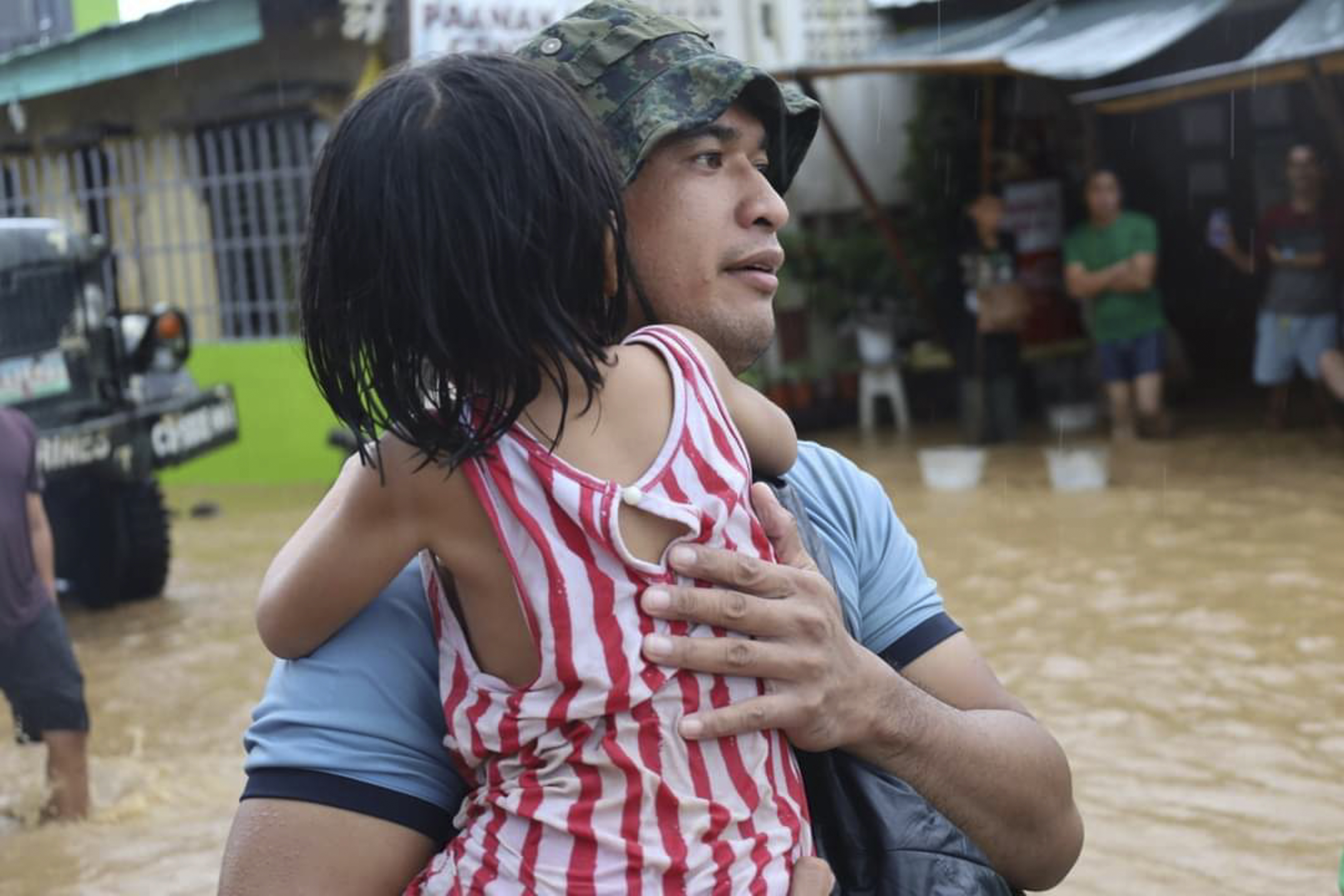 A rescuer carries a child to safer grounds as floods rose due to Tropical Storm Nalgae at Parang, Maguindanao province, southern Philippines on Friday Oct. 28, 2022. (Philippine Coast Guard via AP)