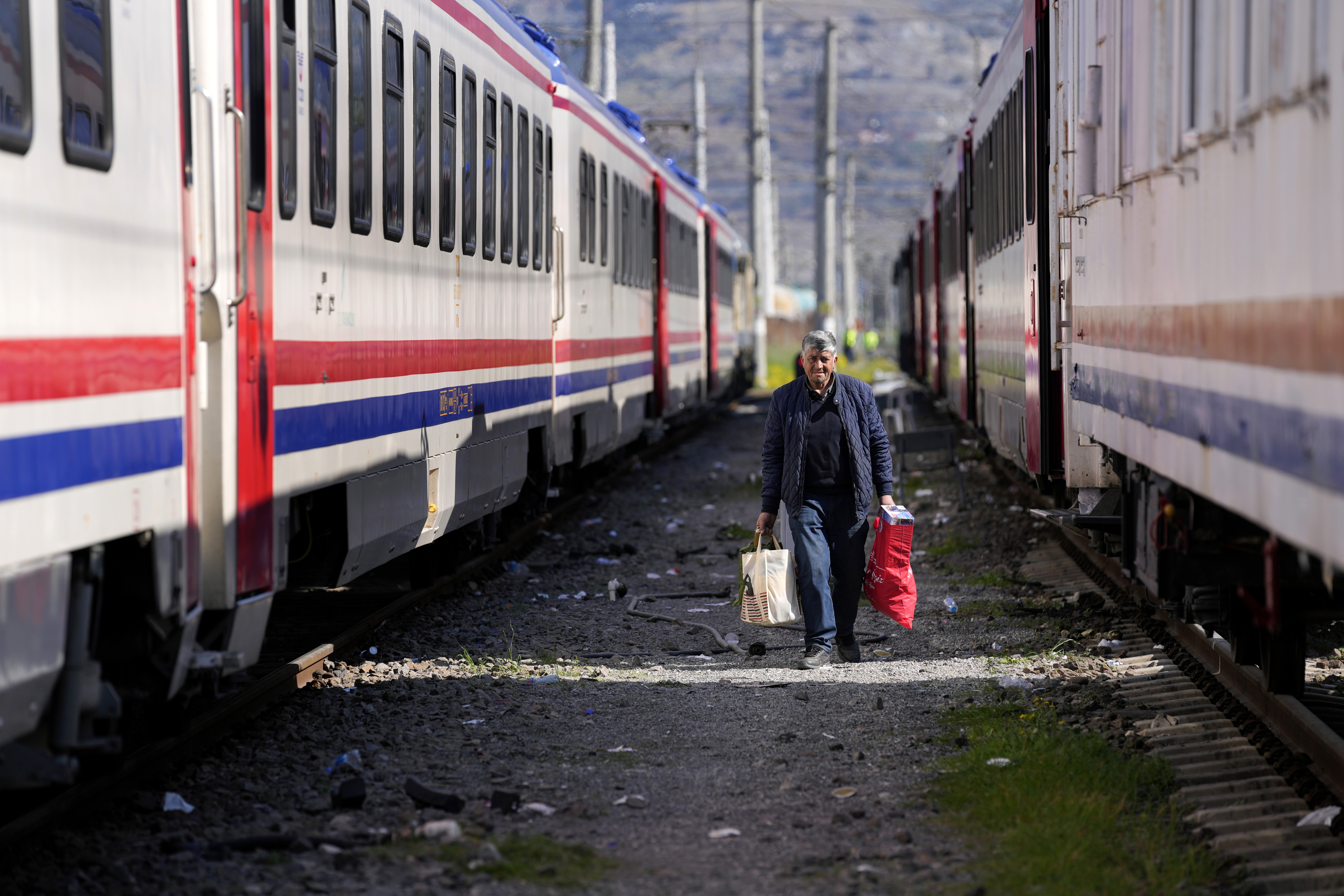 A man walks between trains using as shelters, in Iskenderun city, southern Turkey, Tuesday, Feb. 14, 2023.