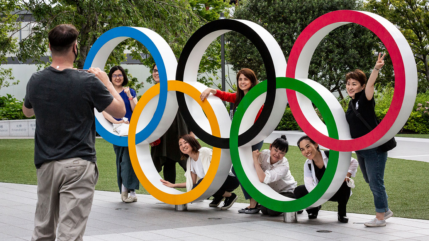People have their photographs taken next to the Olympic Rings in Tokyo, Japan.