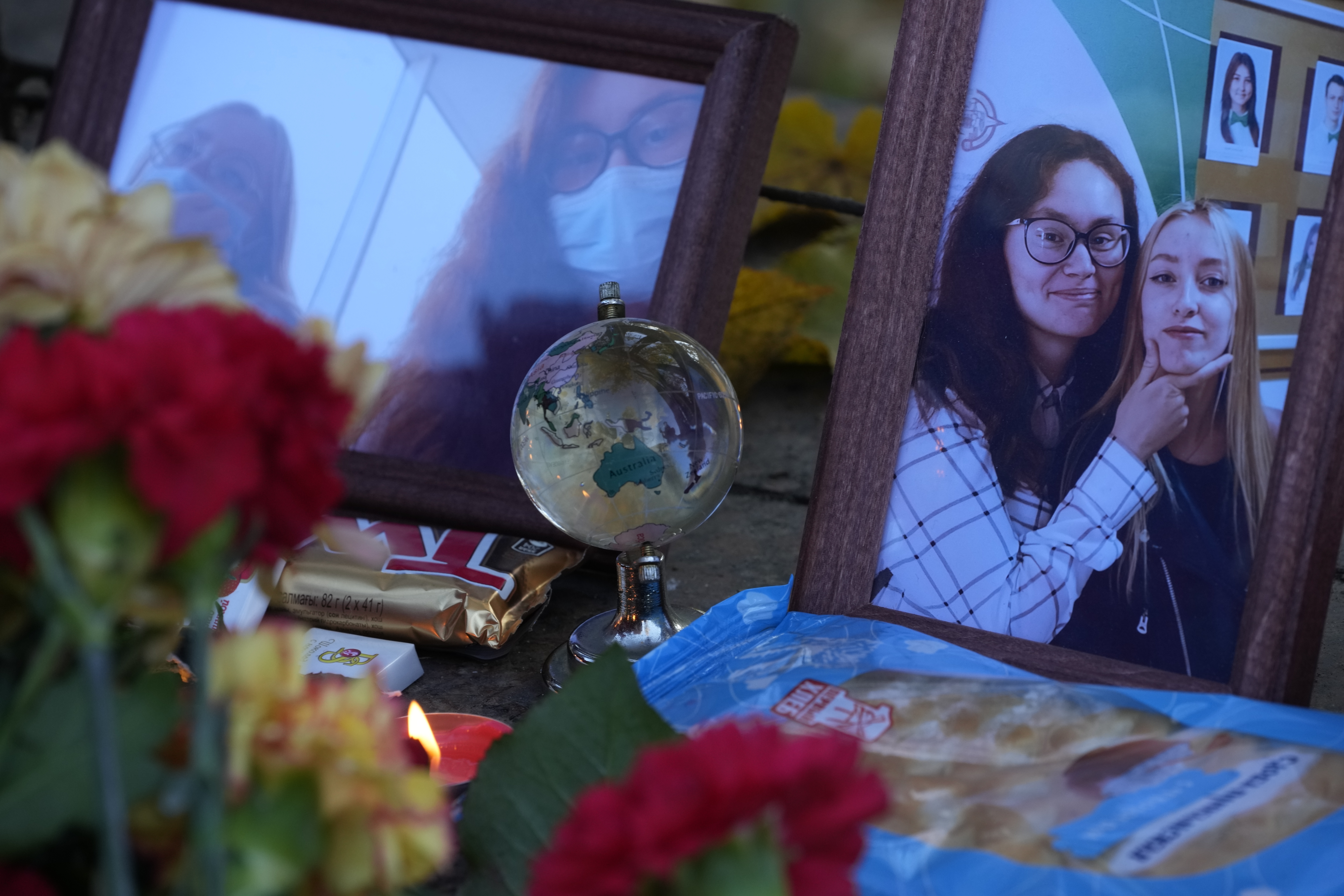 A candle, flowers and portraits of victims of the shooting are displayed on a table outside the Perm State University following a campus shooting.