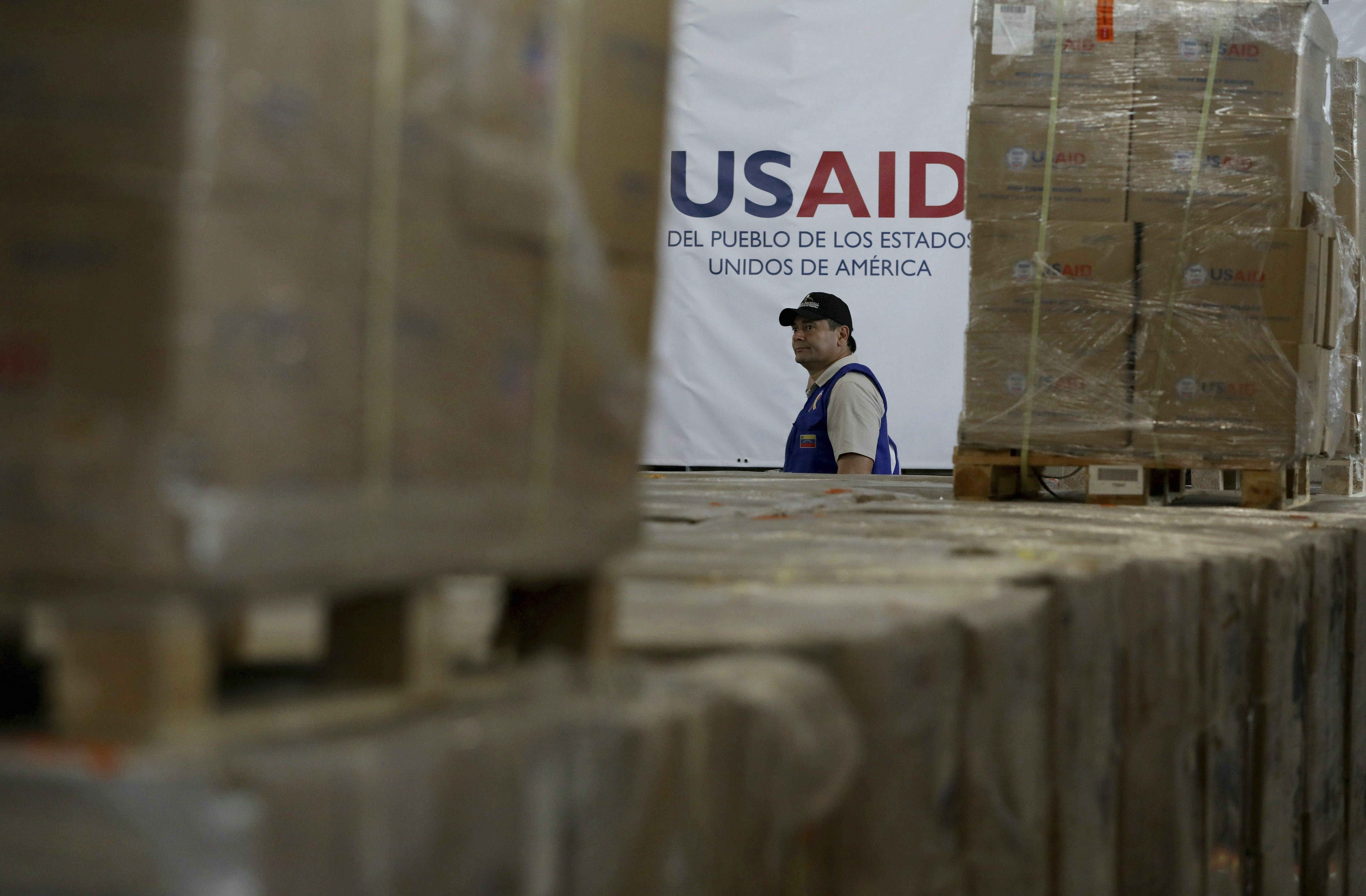   Un hombre pasa por las cajas de ayuda humanitaria de USAID en un almacén en el Puente Internacional de Tienditas en las afueras de Cucuta, Colombia, el 21 de febrero de 2019, en la frontera con Venezuela. 