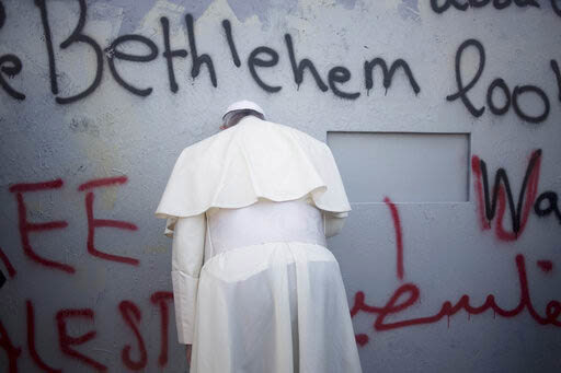 Pope Francis prays at Israel's separation barrier on his way to a mass in Manger Square next to the Church of the Nativity, in the West Bank city of Bethlehem, Sunday, May 25, 2014. 