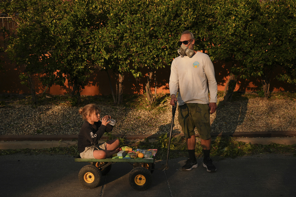 ARCHIVO - El residente Pauly Harter, derecha, arrastra a su hijo Gavin en un carrito durante una caminata el viernes 10 de enero de 2025 en Altadena, California (Foto AP/Jae C. Hong, archivo)