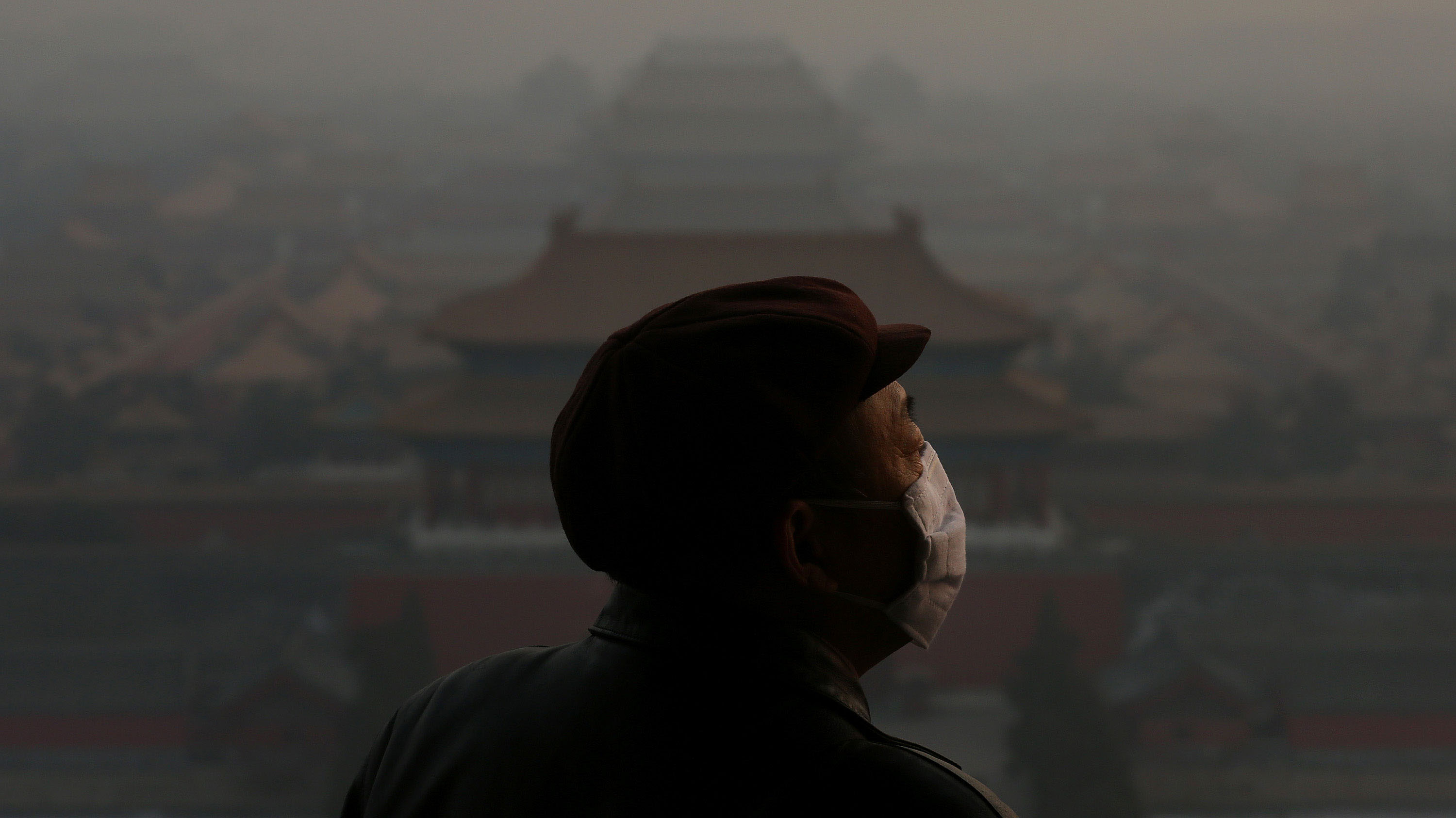 Heavy smog shrouded the Forbidden City in Beijing, China as a tourist looks on.  