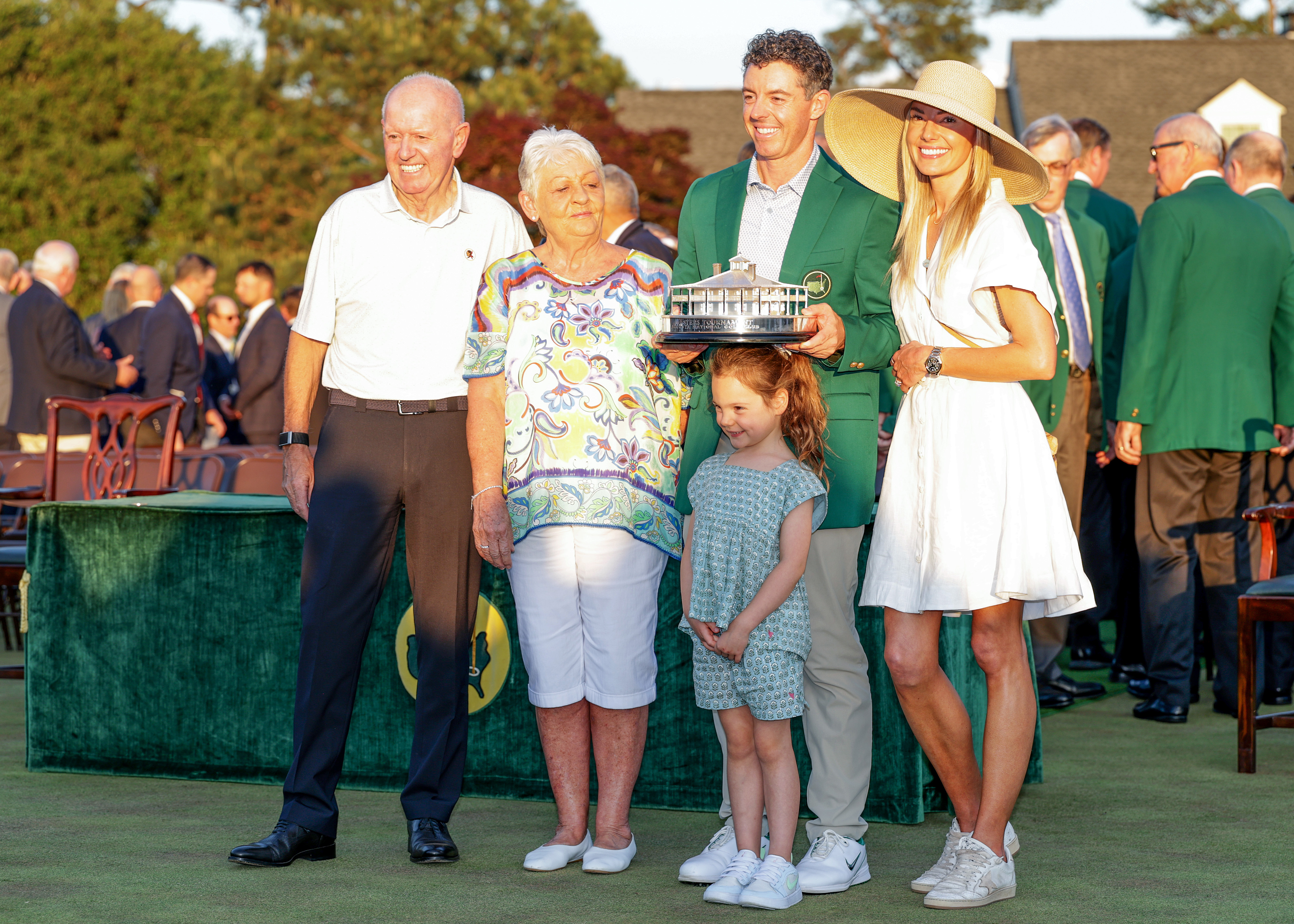 Rory McIlroy of Northern Ireland holds the trophy wearing his Green Jacket with his family his father Gerry McIlroy, his mother Rosie McIlroy his wife Erica and his daughter Poppy at the presentation after the final round of the 2026 Masters Tournament at Augusta National Golf Club on April 12, 2026 in Augusta, Georgia. 
