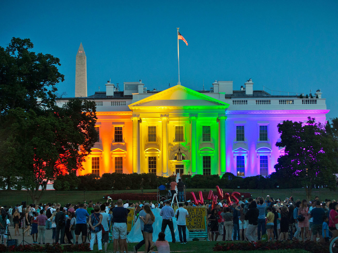 La gente se reúne en el Parque Lafayette de Washington para ver la Casa Blanca iluminada con los colores del arcoíris.