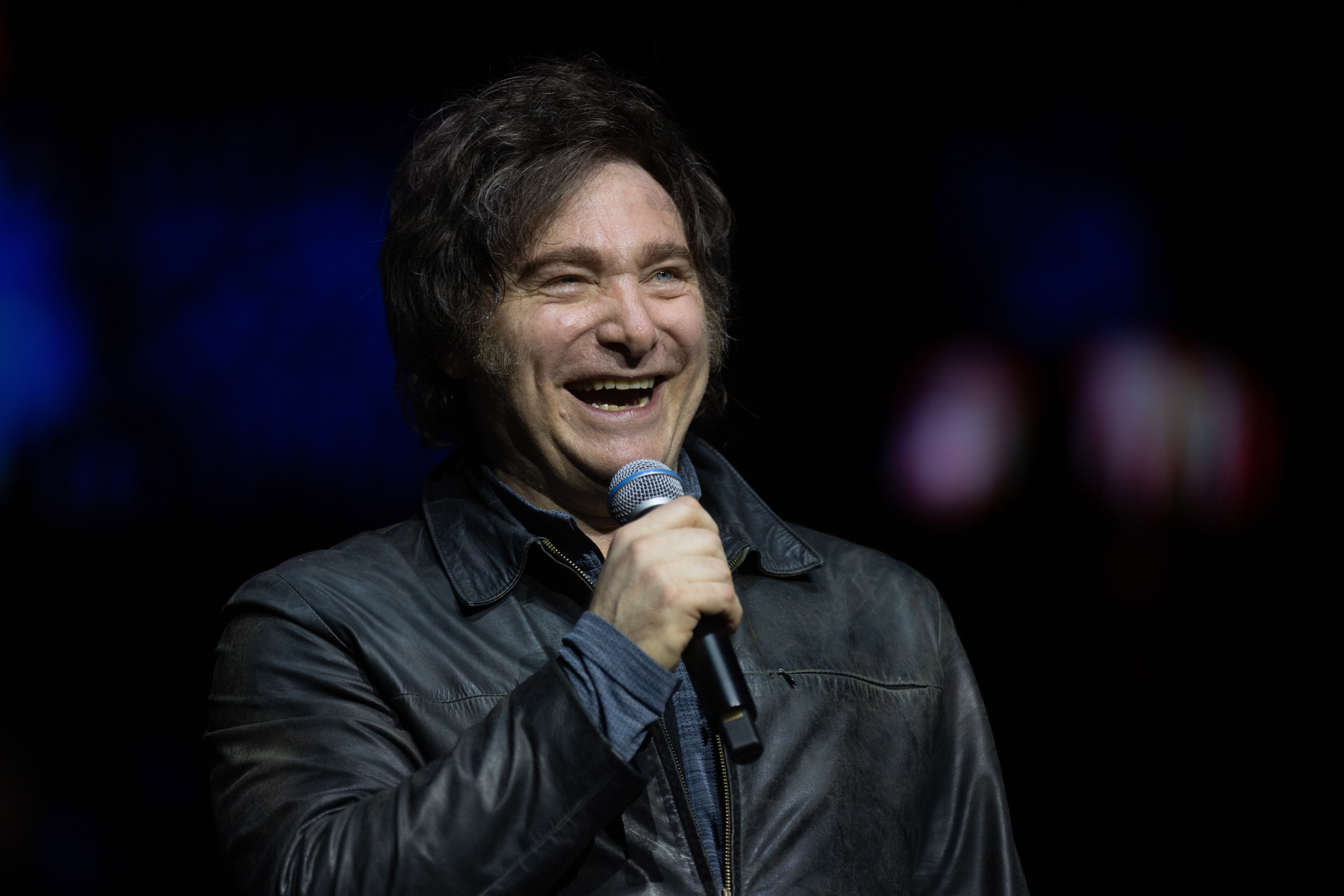 Argentine President Javier Milei smiles in a show with a band during the presentation of his book 'La Construccion del Milagro' at Movistar Arena on October 06, 2025 in Buenos Aires, Argentina.