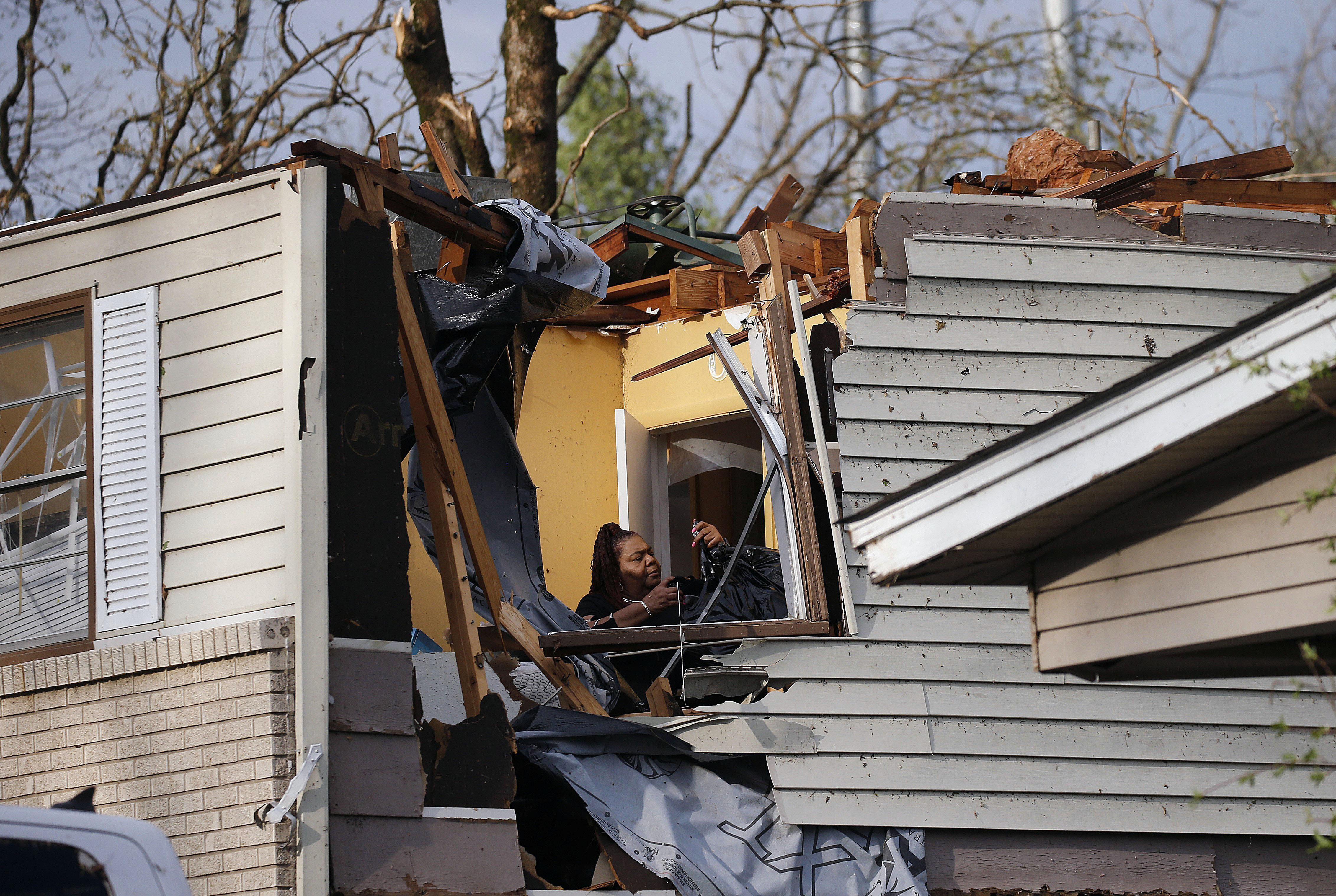 A woman collects belongings from a family members home after the roof was ripped off from a tornado on Oakview Drive in North Little Rock, Ark. Friday, March 31, 2023.