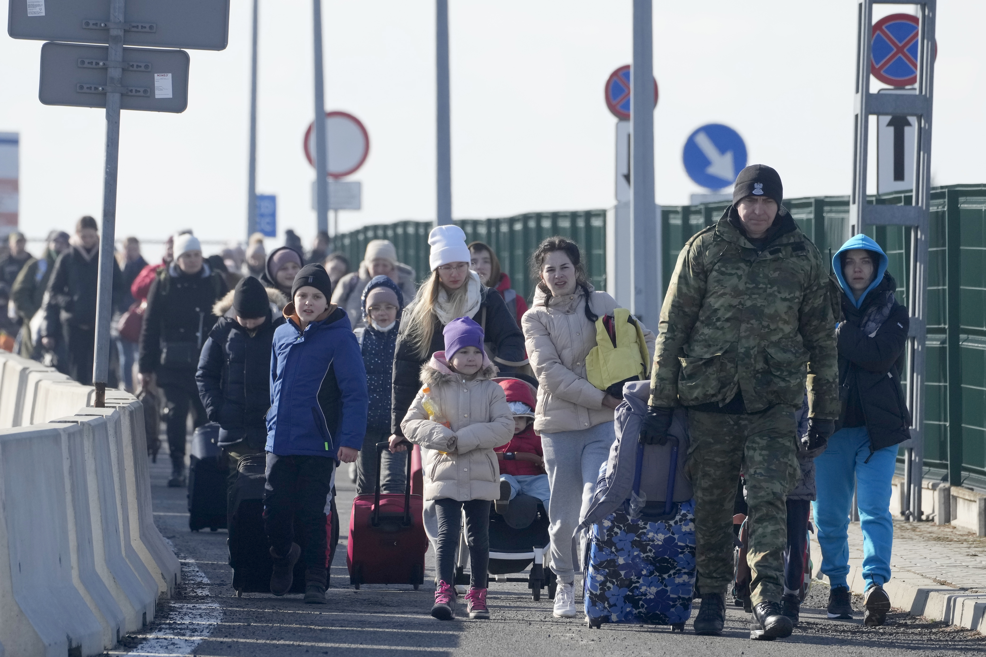 A Polish border guard assists refugees from Ukraine as they arrive to Poland at the Korczowa border crossing, Poland, Saturday, Feb. 26, 2022. (AP Photo/Czarek Sokolowski)