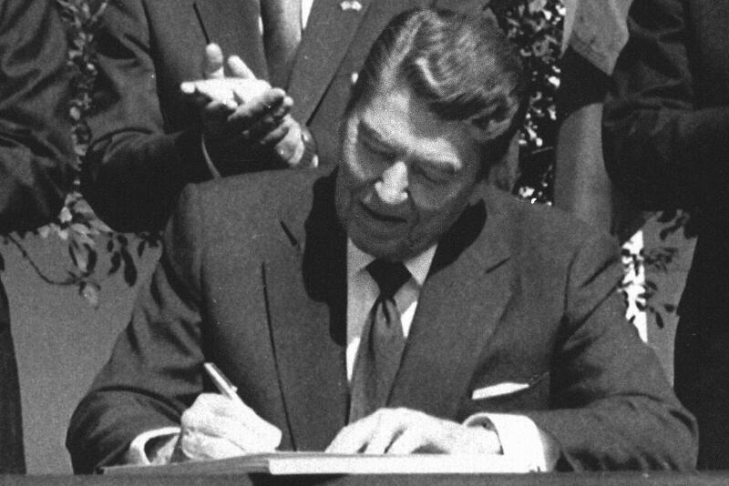 President Ronald Reagan signs legislation implementing the U.S.-Canada free trade agreement during a ceremony at the White House