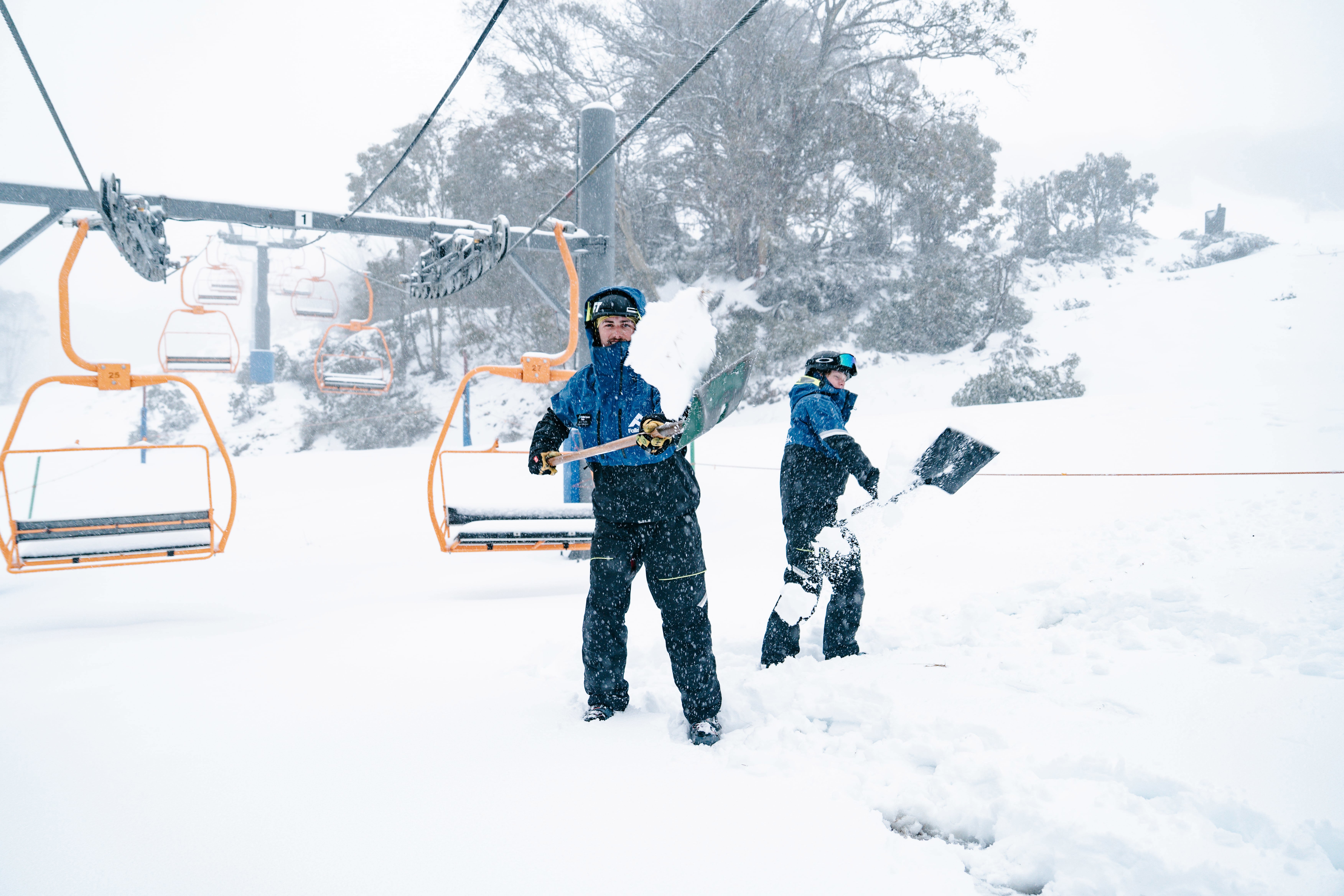 Skiers work to clear snow froma chairlift at Falls Creek, Victoria.