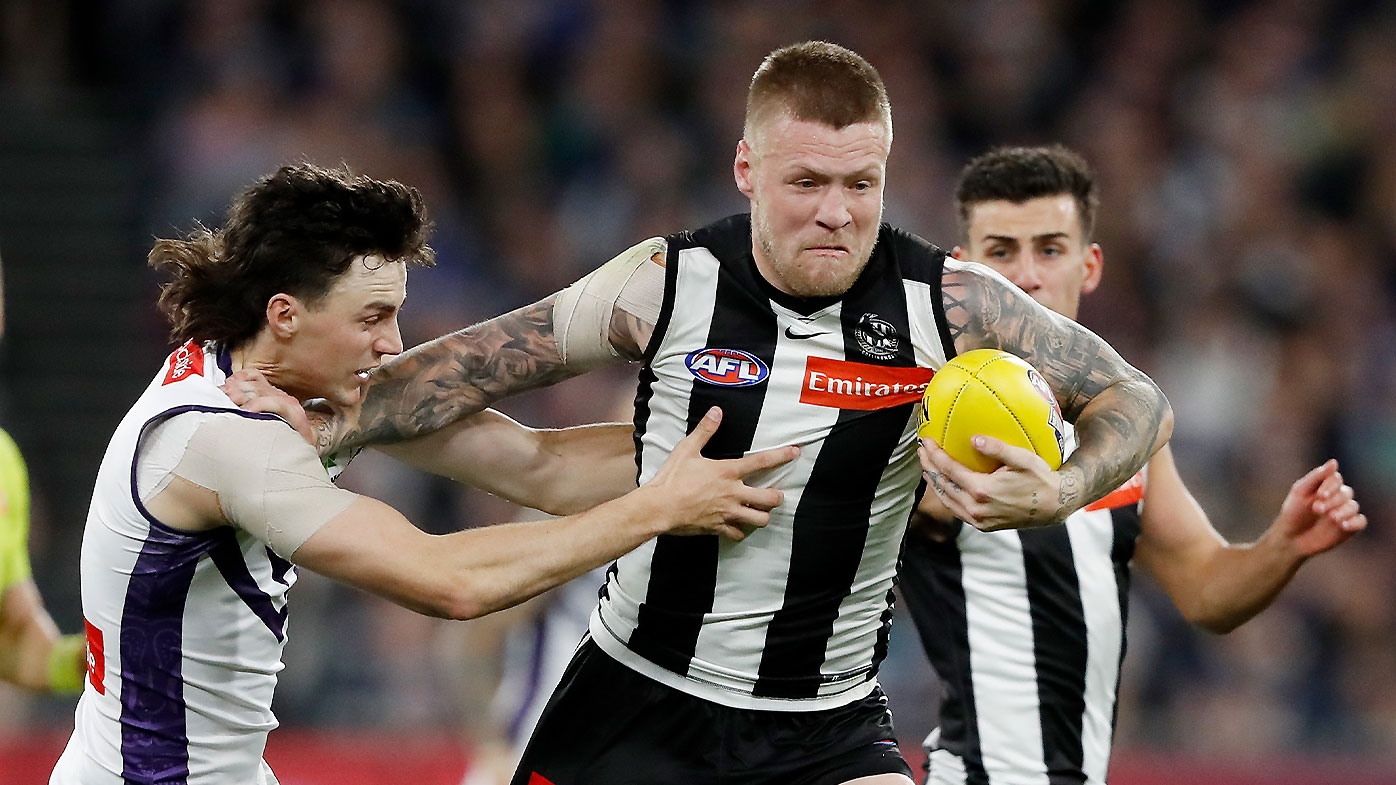 Collingwood's Jordan De Goey fends off a tackle from Fremantle's Jordan Clark