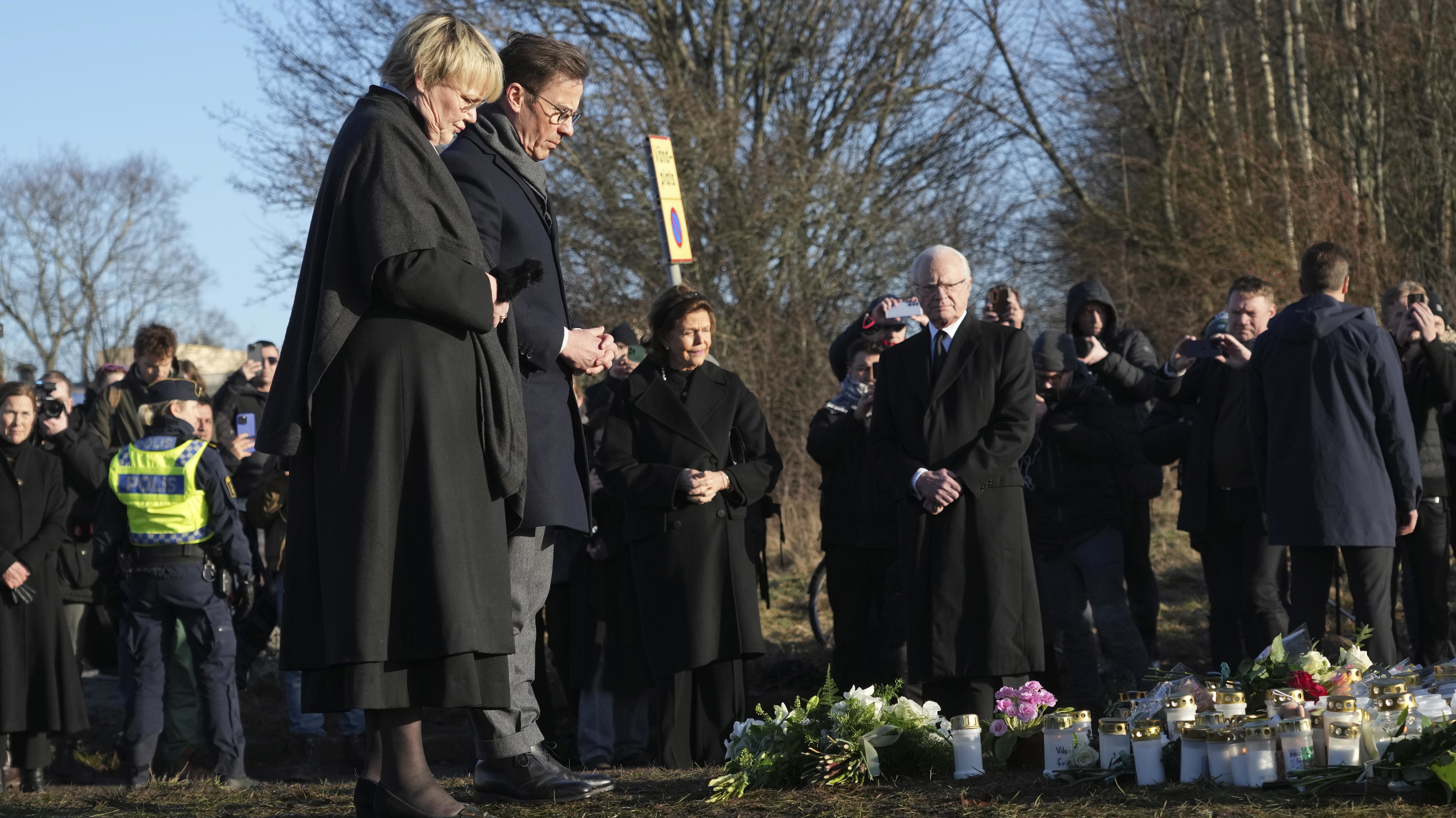 Sweden's Prime Minister Ulf Kristersson and his wife Birgitta Ed place flowers at a memorial near the scene of a shooting on the outskirts of Orebro, Sweden