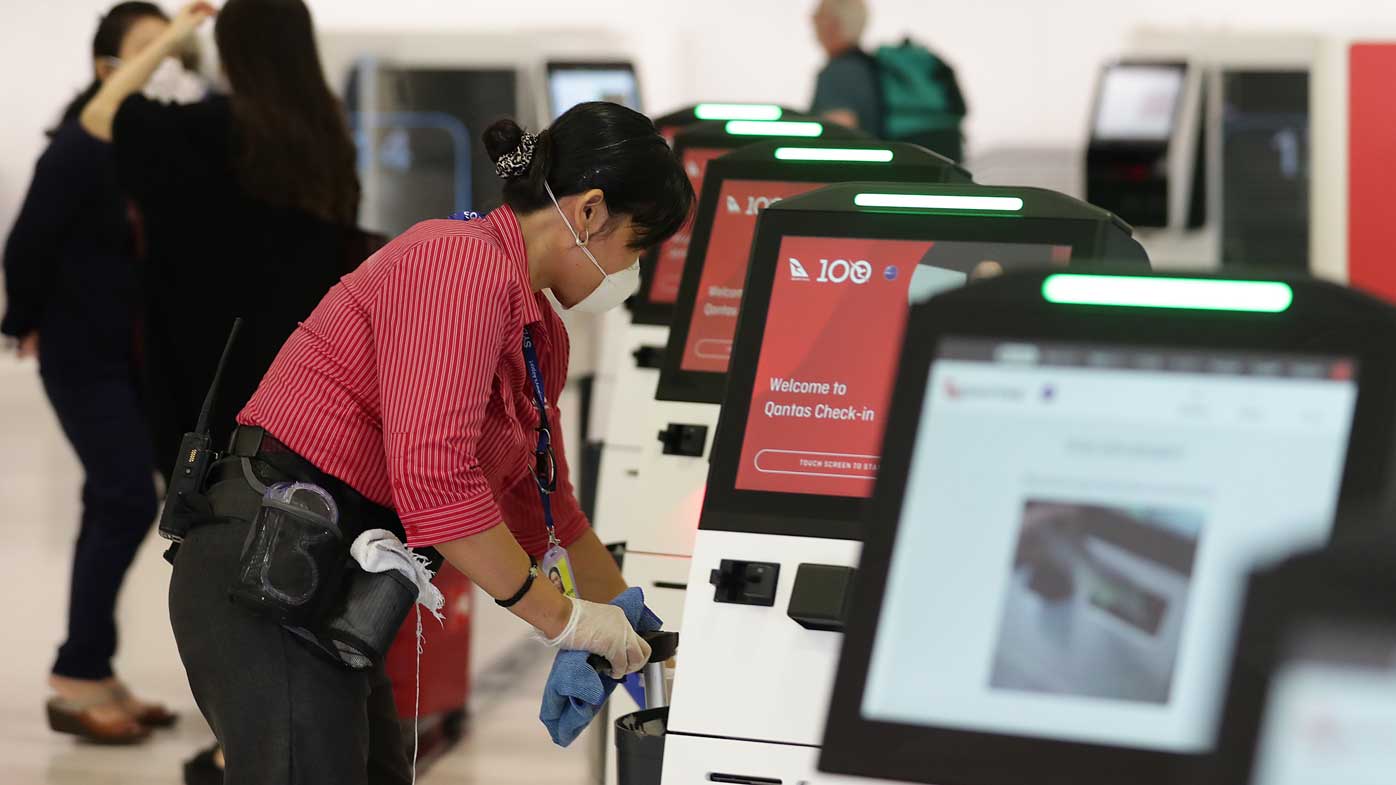 An airport worker cleans a machine at the Qantas check-in area at Sydney Airport.