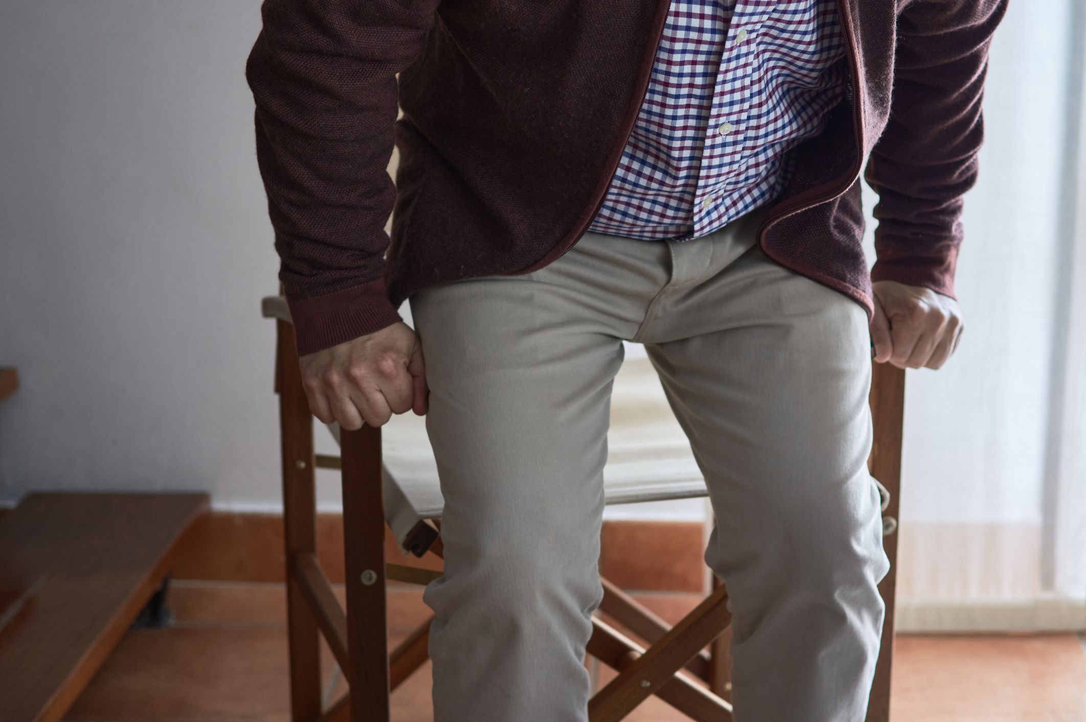 Horizontal photo. Selective blur. A mature man has difficulty getting up from an armchair in the living room of his home.