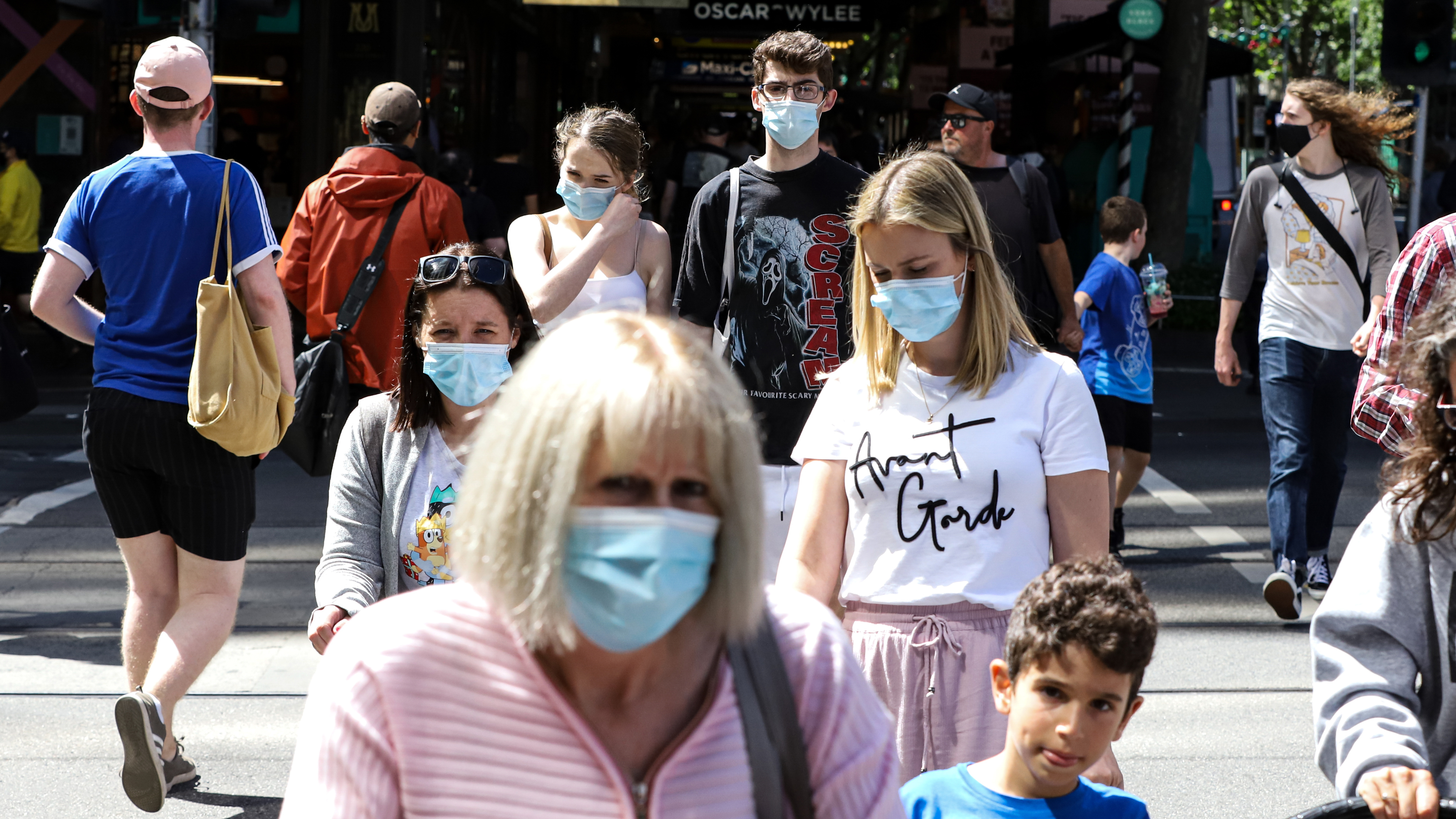 People wearing face masks cross Collins Street in Melbourne, Australia.