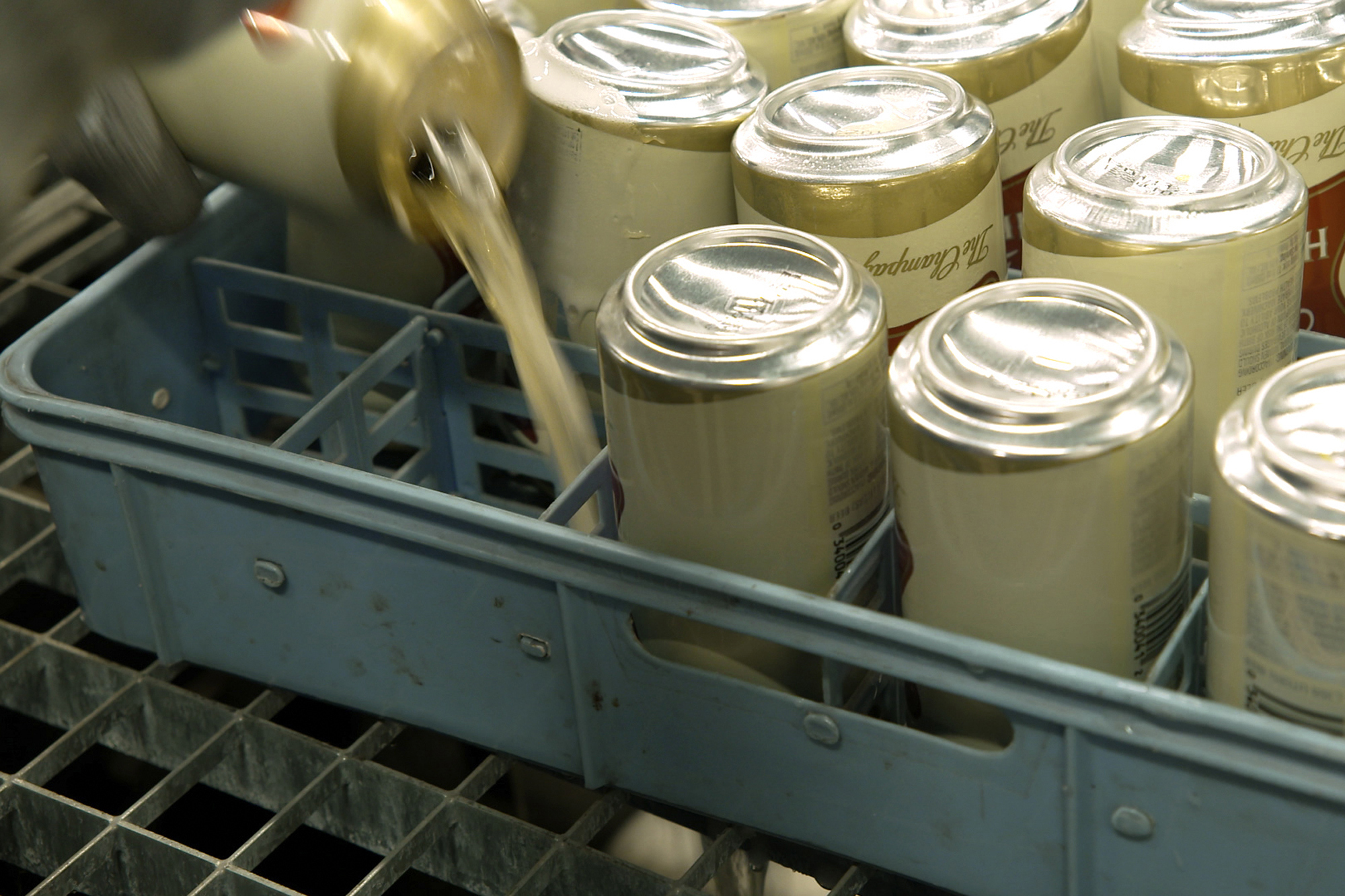 A worker pours out the contents of cans of Miller High Life beer prior to them being crushed at the Westlandia plant in Ypres, Belgium, Monday, April 17, 2023. 