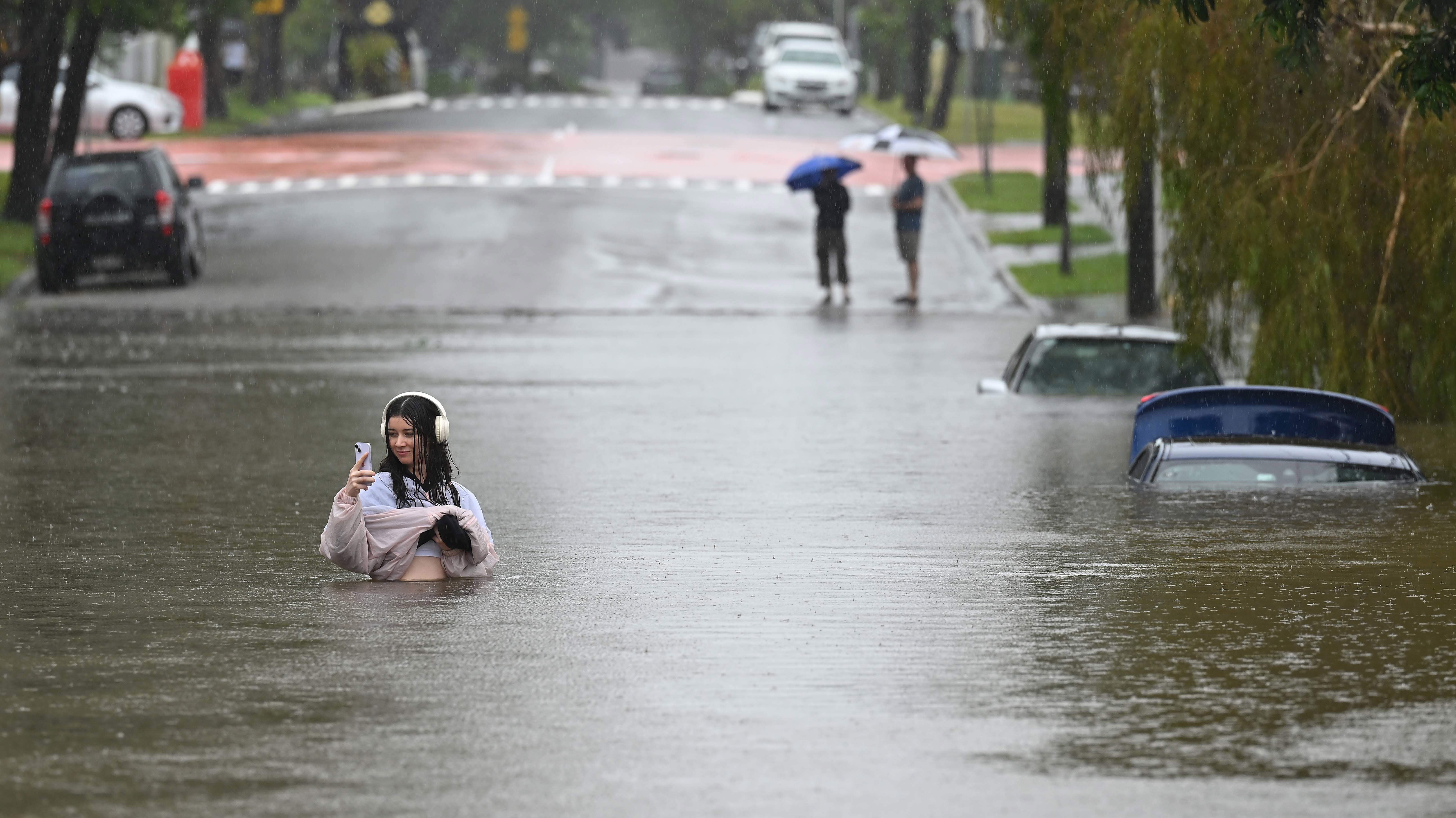 A resident wades in flooded Edmonstone Street in the suburb of Newmarket in Brisbane.