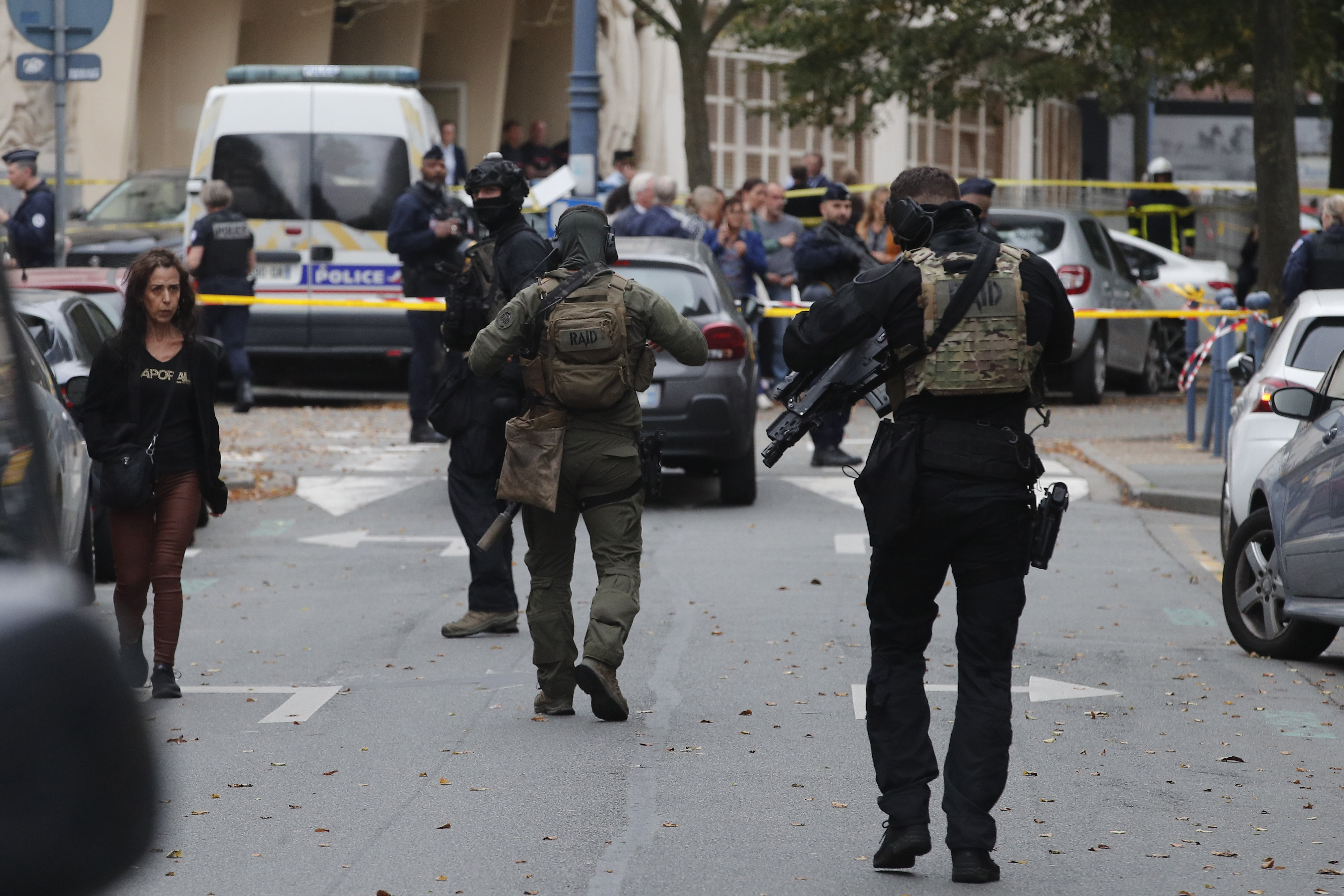 Elite police officers of the RAID squad patrol after a man armed with a knife killed a teacher and wounded two others at a high school in northern France, Friday, Oct. 13, 2023 in Arras.  