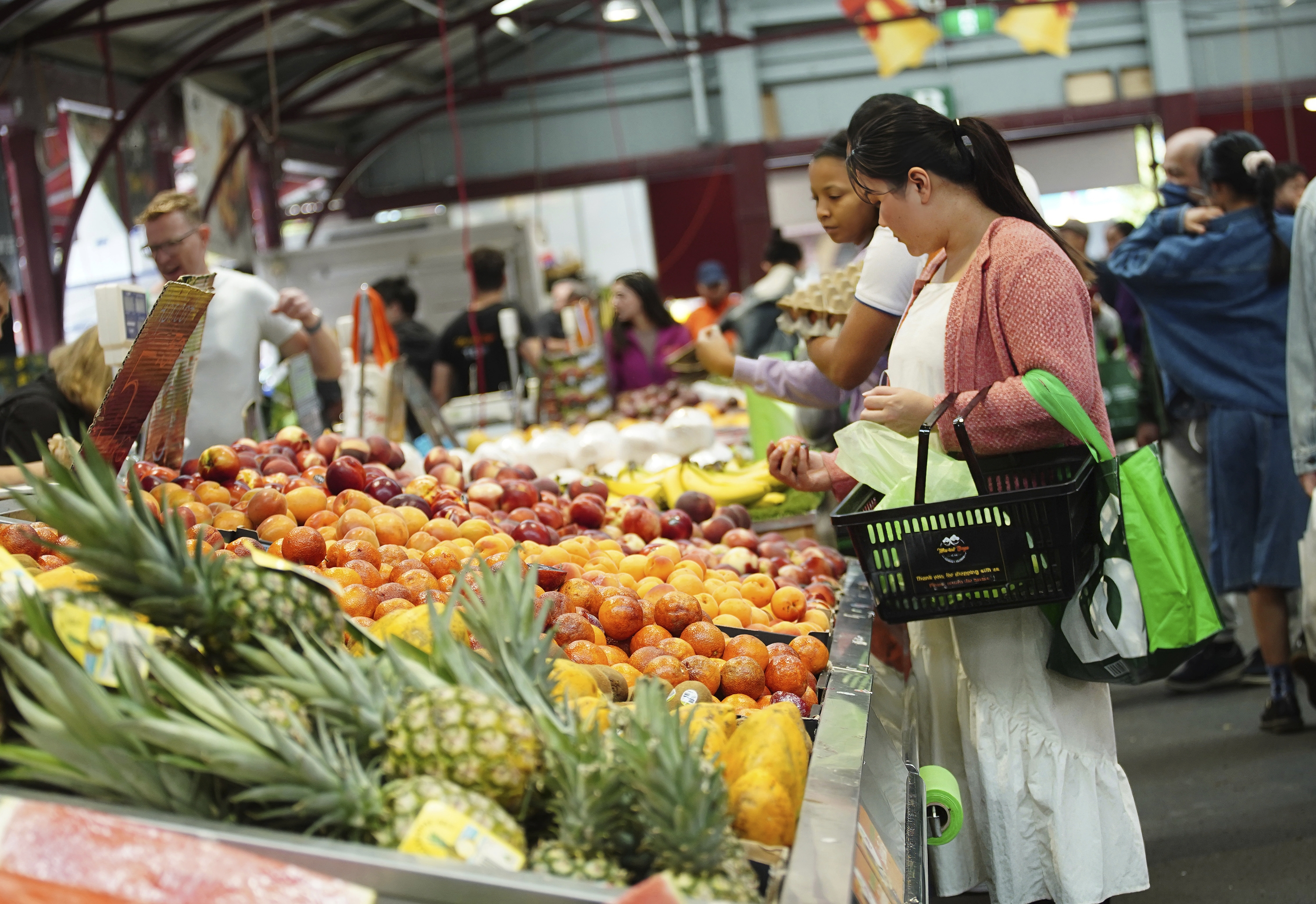 General photo of people shopping for fruits and vegetables at the Queen Vic Market.