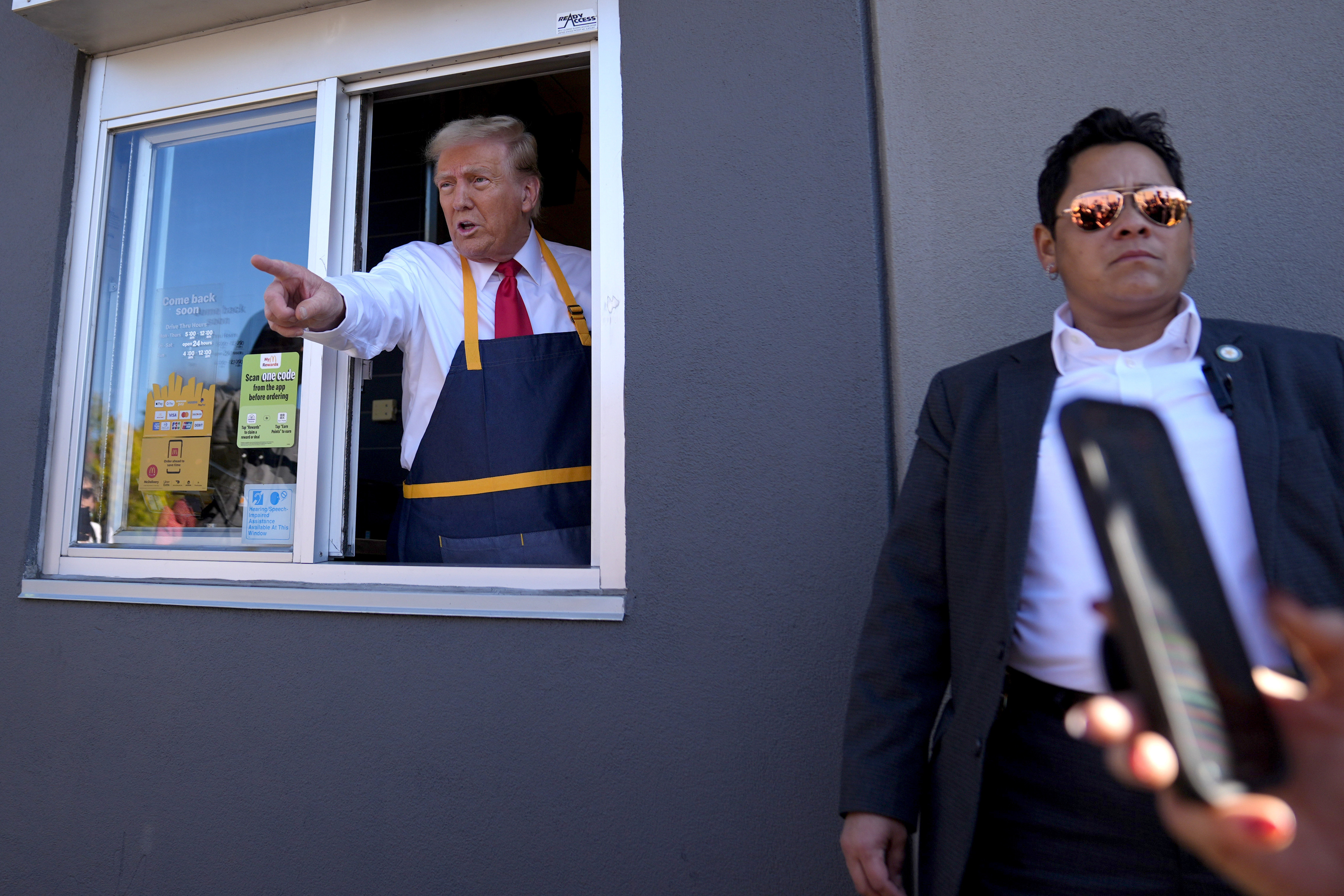 Un empleado entrega una orden al expresidente Donald Trump, candidato presidencial republicano, durante una visita a McDonald's en Feasterville-Trevose, Pensilvania, el domingo 20 de octubre de 2024. (Doug Mills/The New York Times vía AP, Pool)