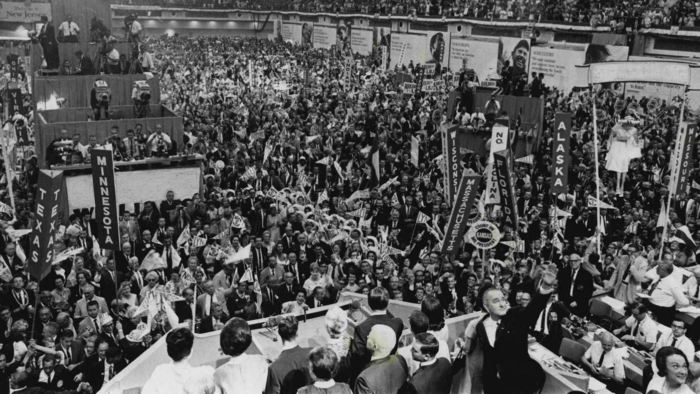 Antes de 1968, los candidatos presidenciales se decidían mediante votación en la convención. En esta fotografía de 1964, el presidente Lyndon Johnson saluda en primer plano después de aceptar la nominación.