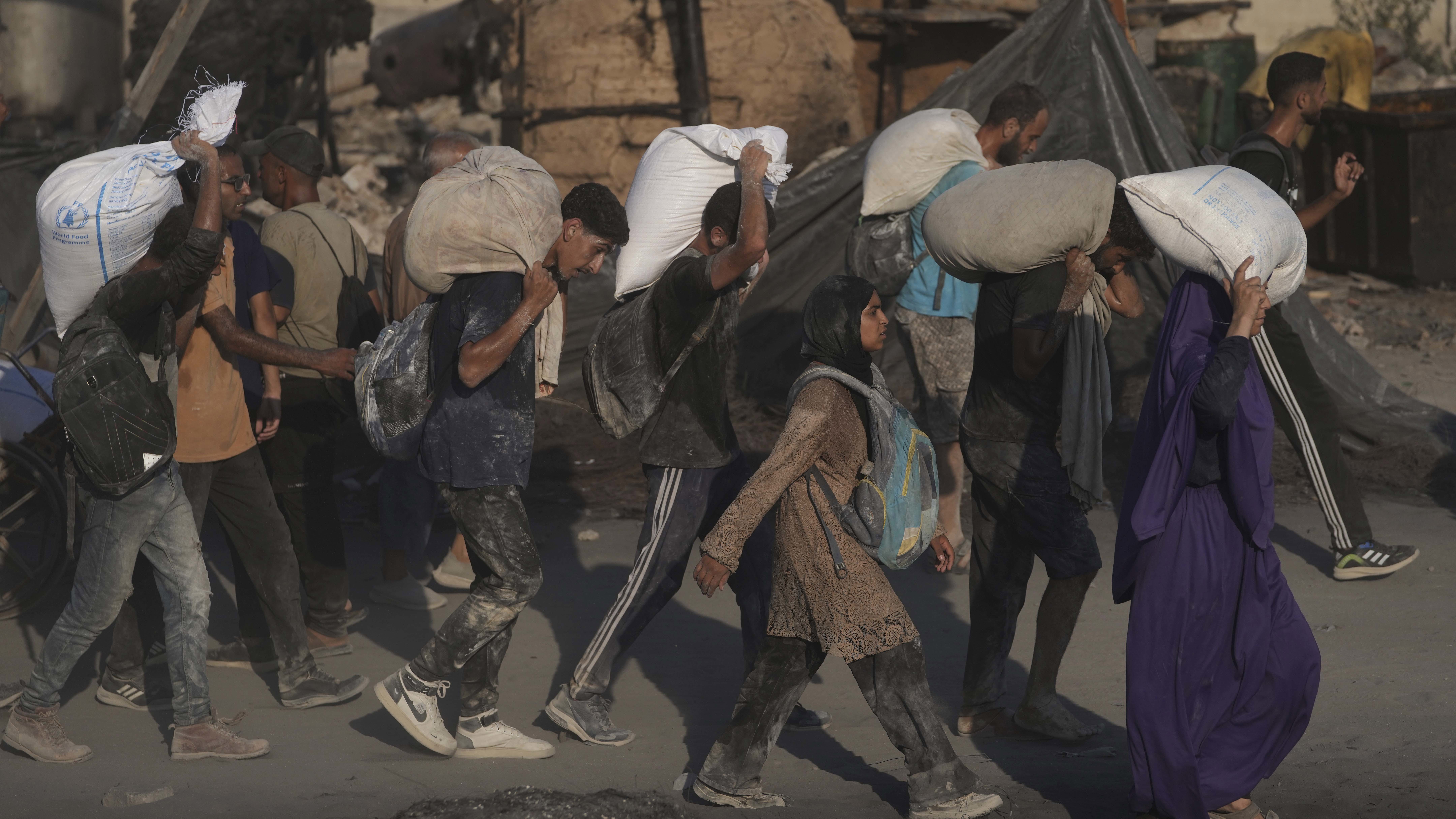 Palestinians carry sacks of flour unloaded from a humanitarian aid convoy that reached Gaza City from the northern Gaza Strip.
