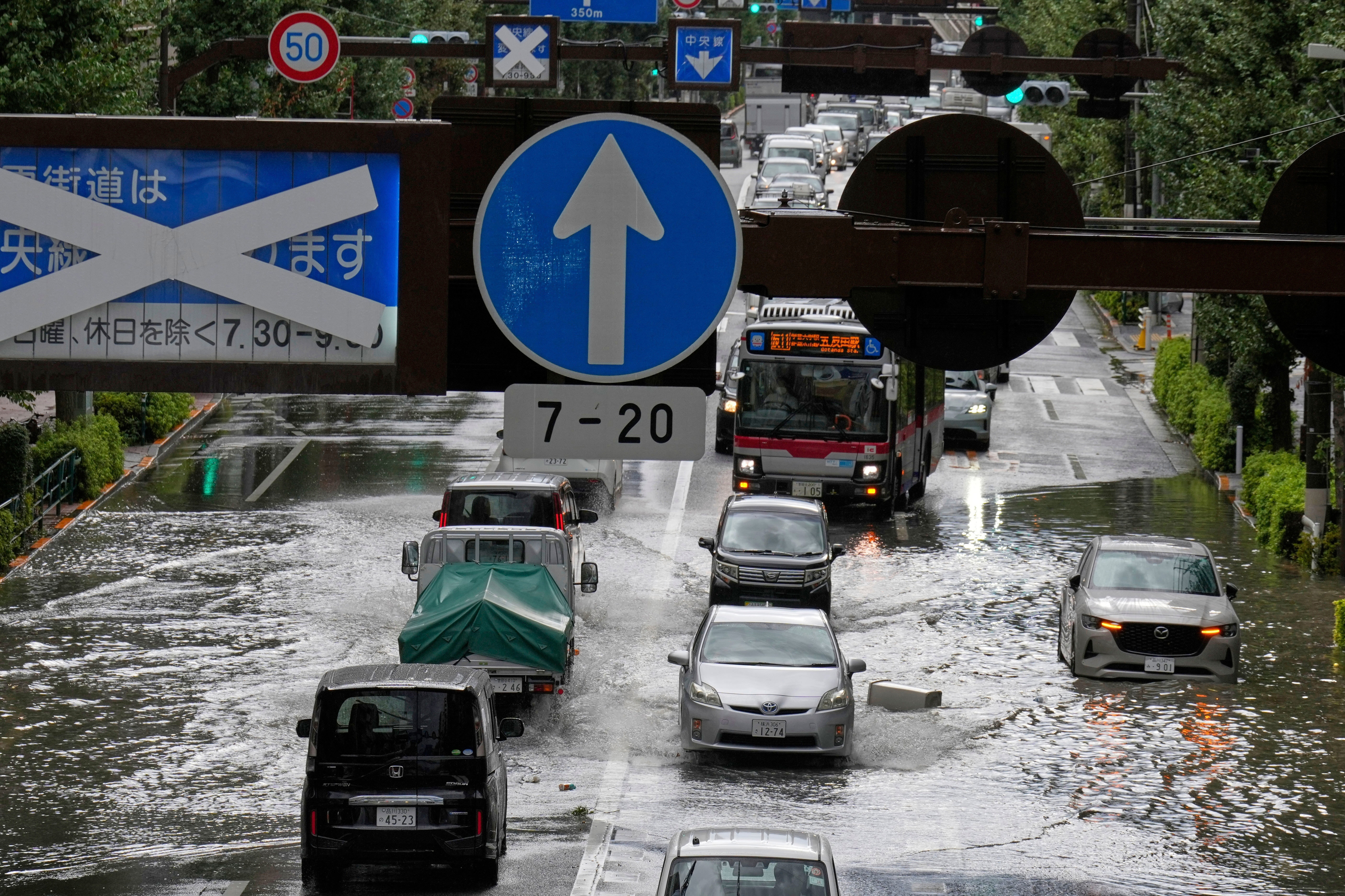 Vehicles drive through a flooded road.