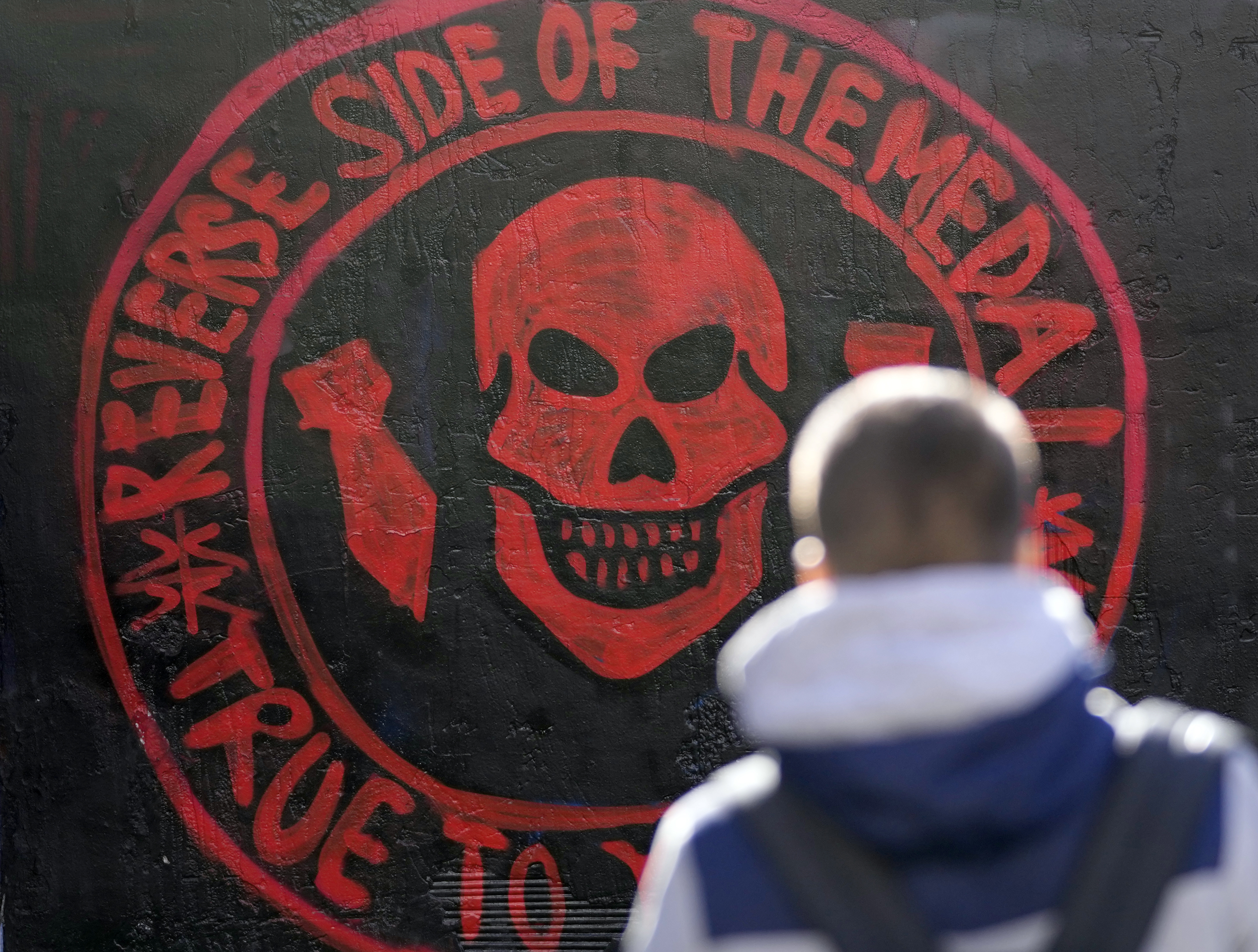 A boy walks by a repainted mural depicting the logo of Russia's Wagner Group on a wall in Belgrade, Serbia.