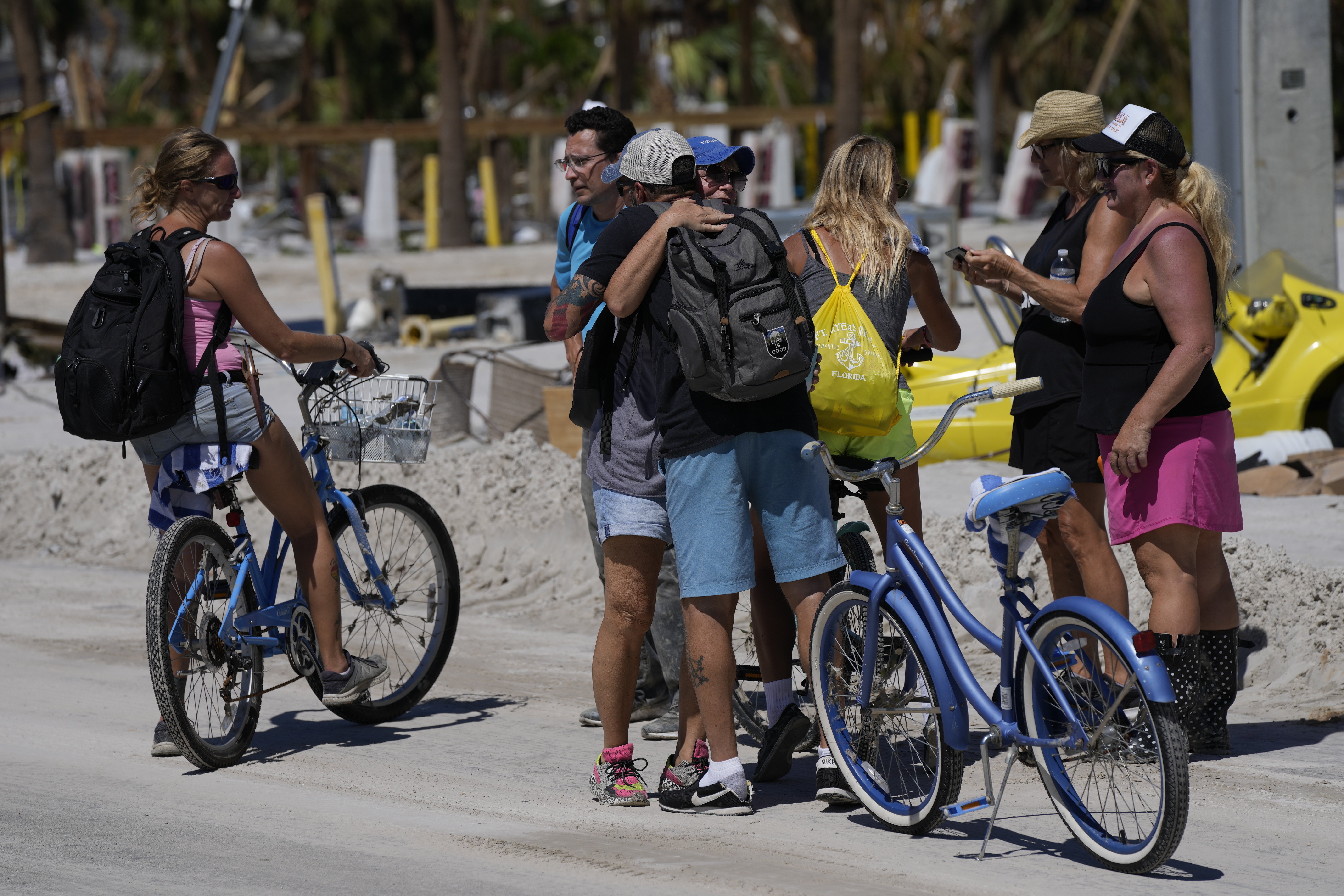 Friends seeing each other for the first time since the passage of Hurricane Ian stop to embrace, as they walk and bike on the island to collect belongings from whatever remains of their homes, in Fort Myers Beach, Florida, Friday, September 30, 2022 