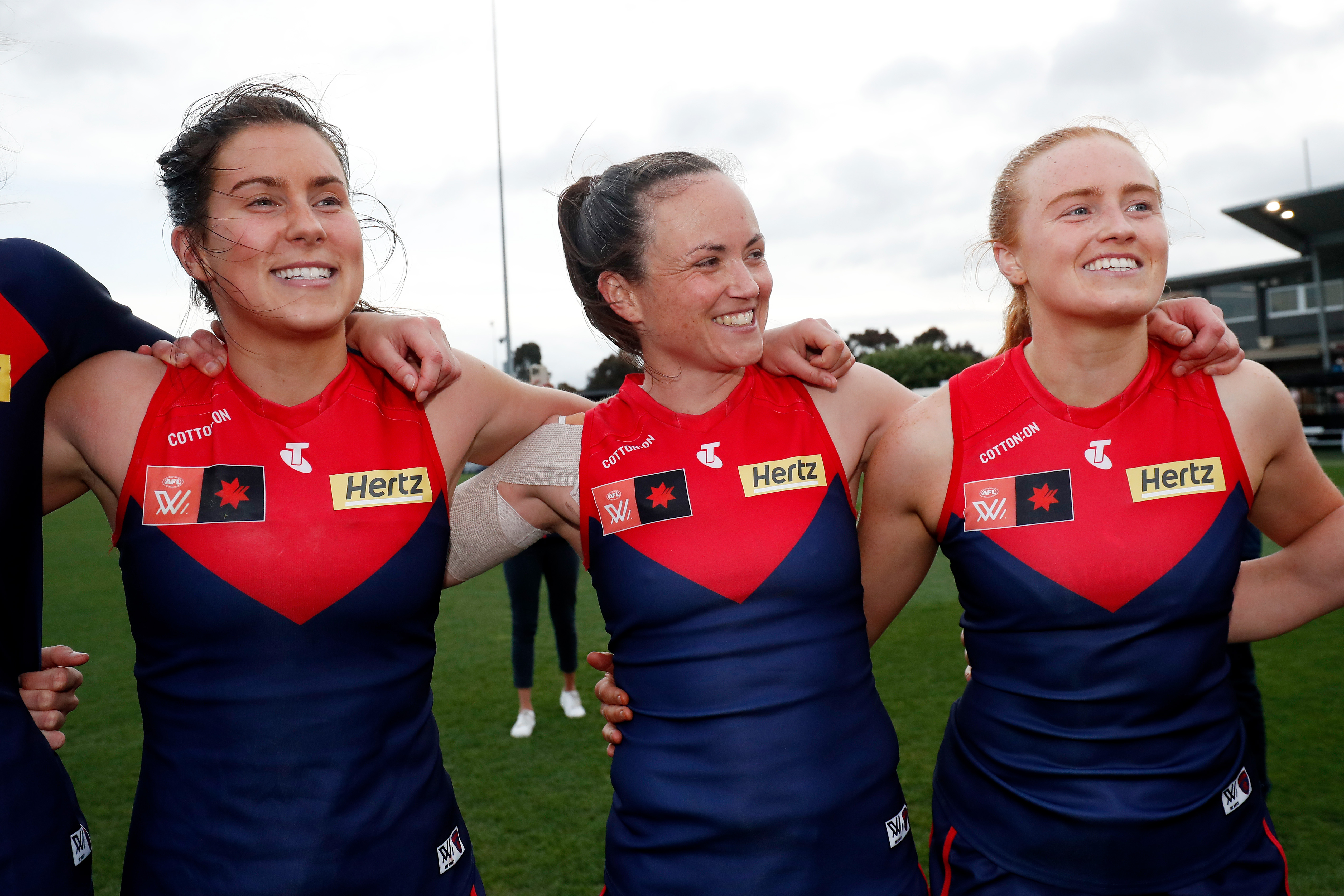 Libby Birch, Daisy Pearce and Blaithin Mackin of the Demons sing the team song.